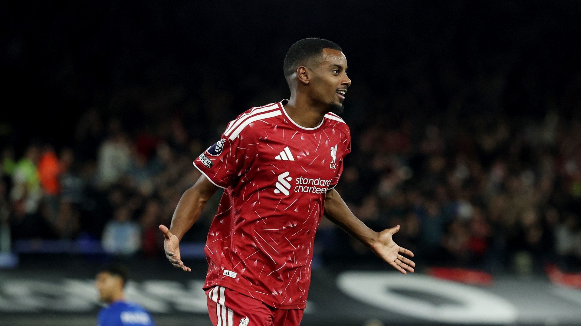 En fotbollsspelare i Liverpools röda tröja firar under en match.