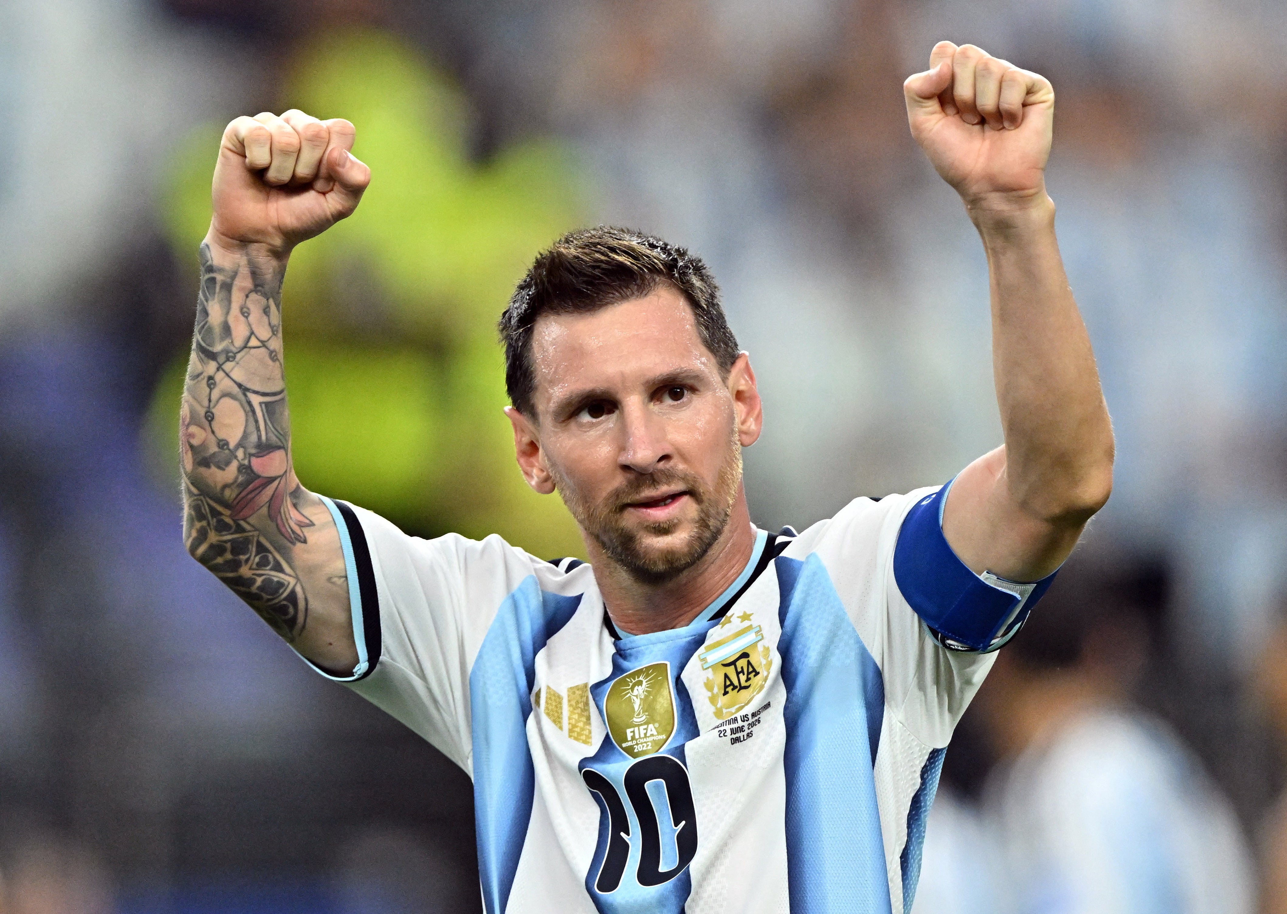 Fotbollsspelare i Argentinas nationaltröja firar med båda närvarna upphöjda.