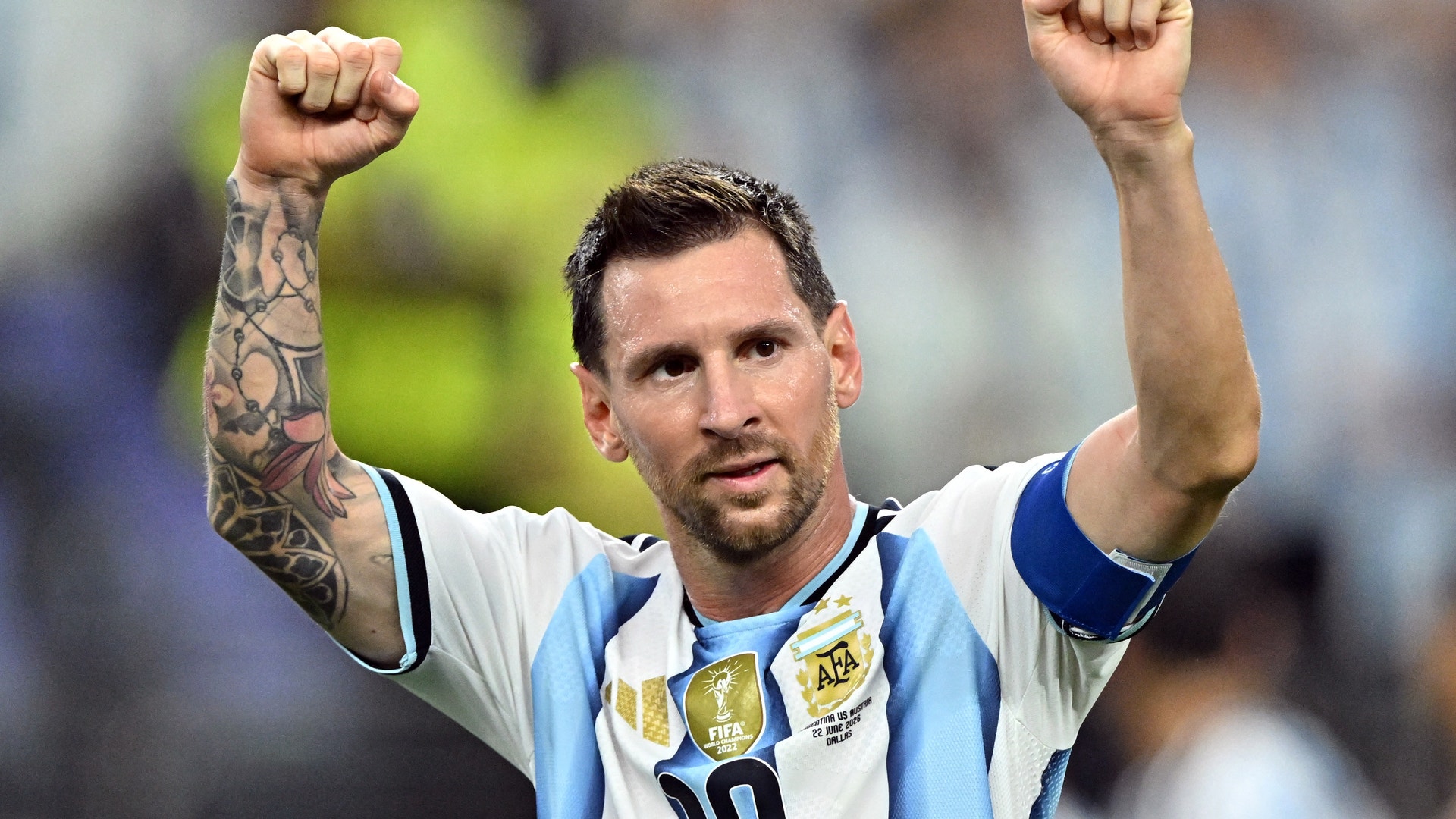 Fotbollsspelare i Argentinas nationaltröja firar med båda närvarna upphöjda.
