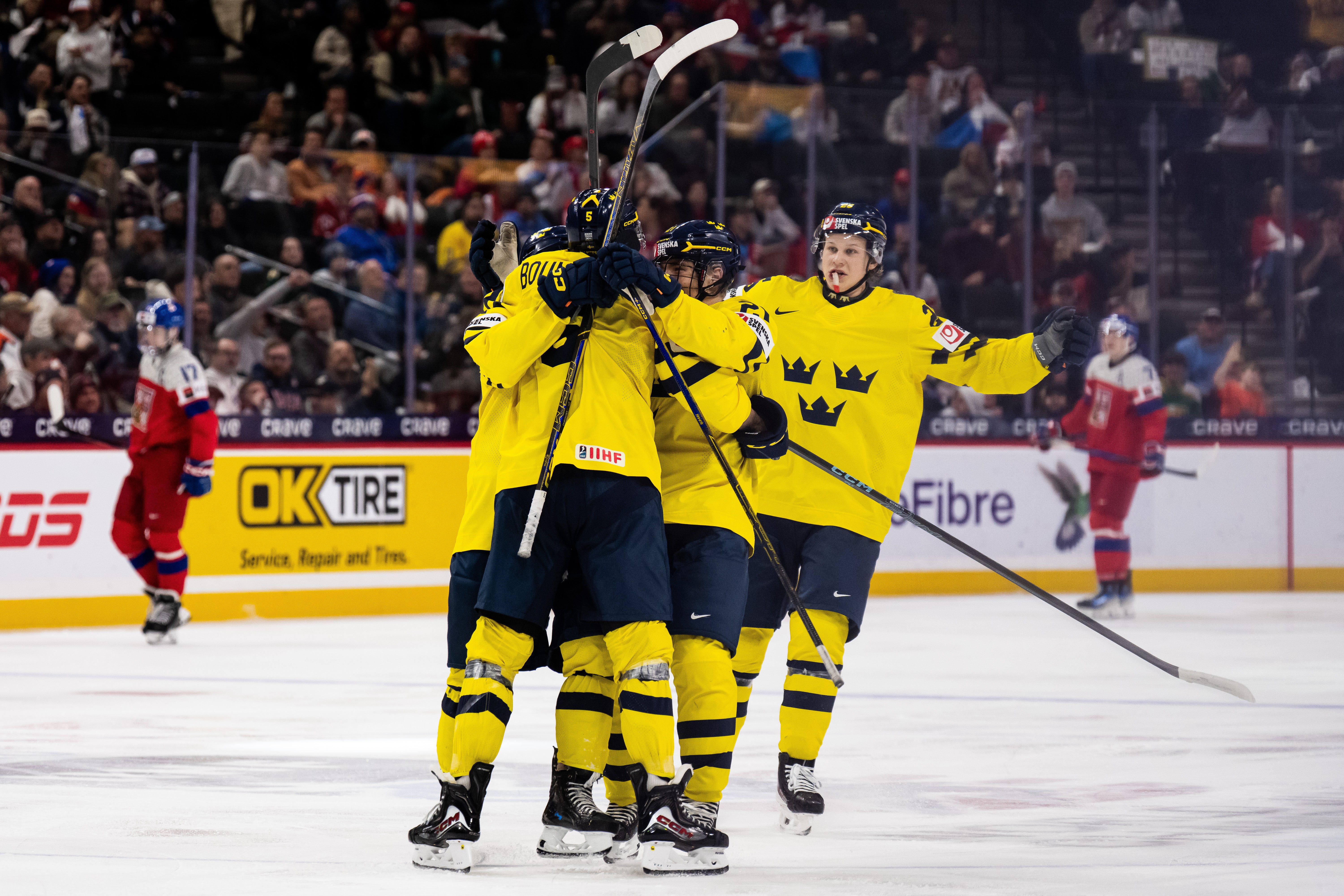 Svenska ishockeyspelare firar tillsammans på isen under en match.