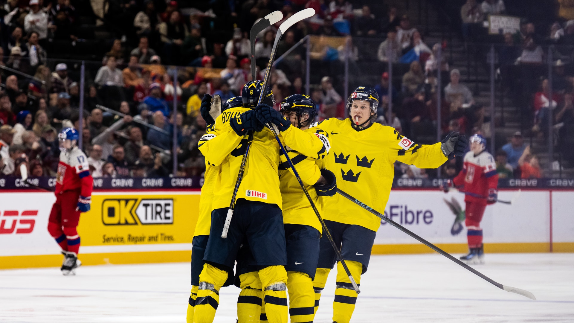 Svenska ishockeyspelare firar tillsammans på isen under en match.