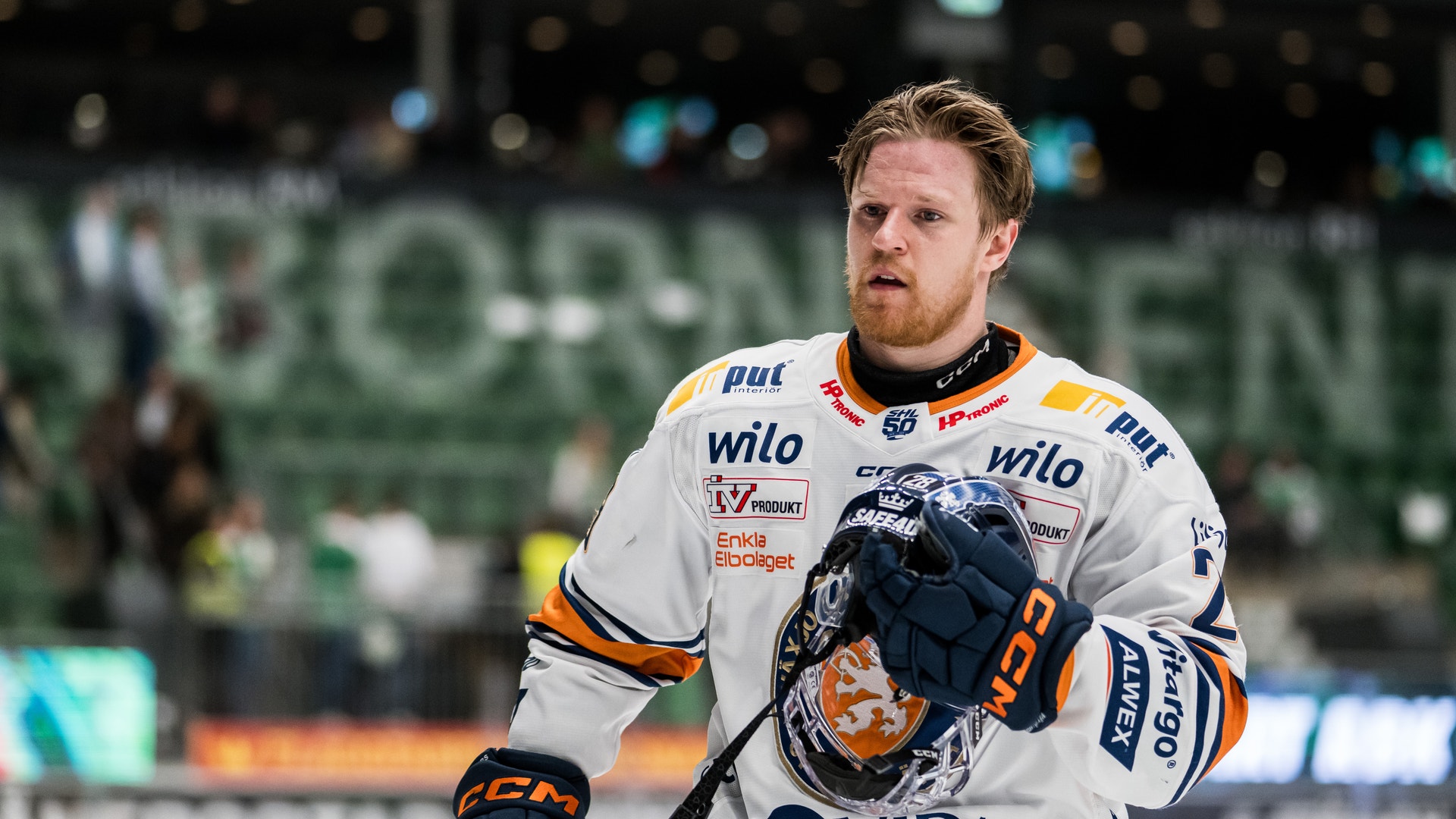 Ishockeyspelare i vit tröja med orange och blå detaljer under match.