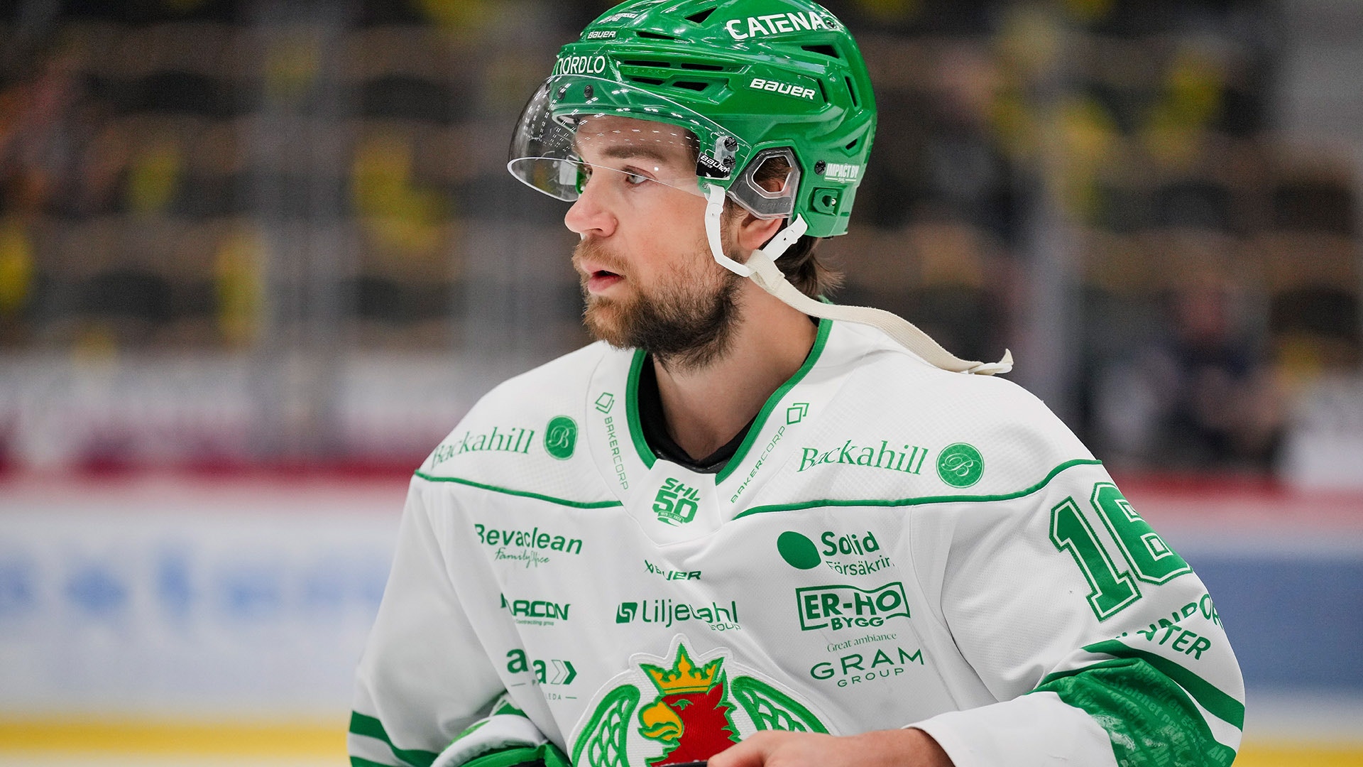 Ishockeyspelare i grönt och vitt lag med hjälm under en match.
