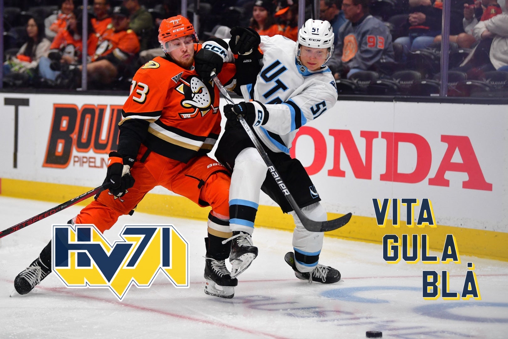 Två ishockeyspelare kämpar om pucken under en match. En spelare i orange dräkt och en i vit dräkt är inblandade i en intensiv duell på isen.