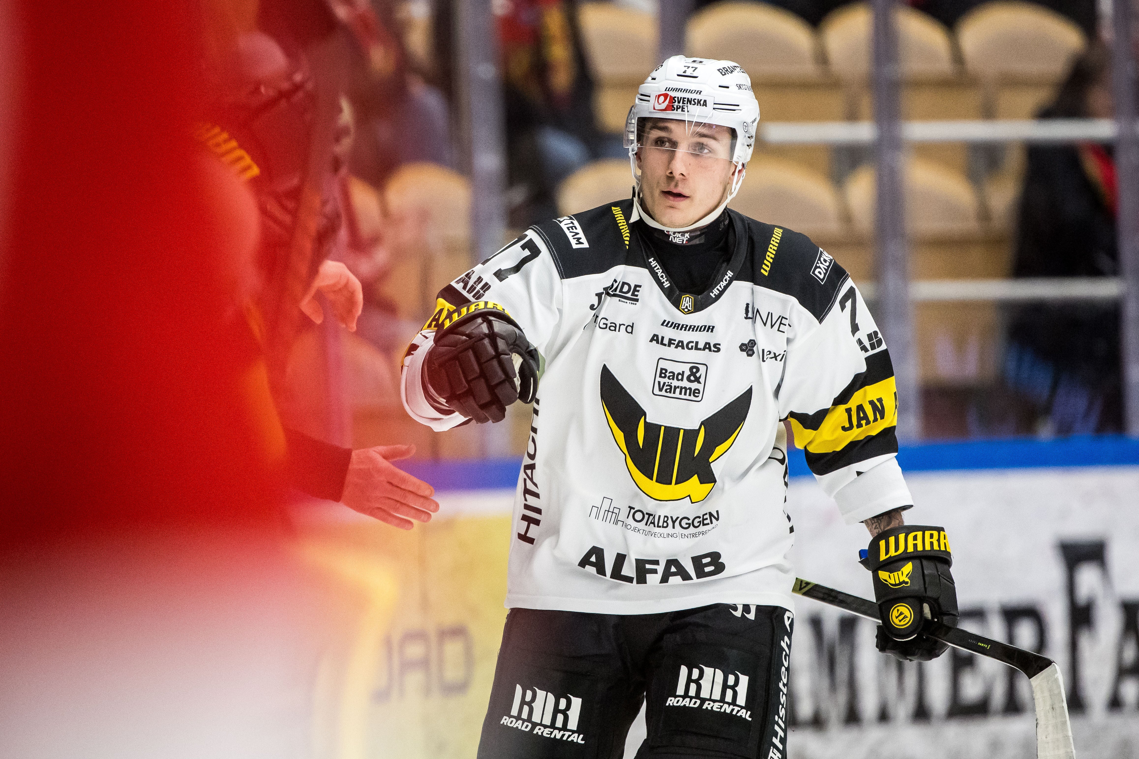Ishockeyspelare i vit och svart matchdräkt gestikulerar under en ishockeymatch.