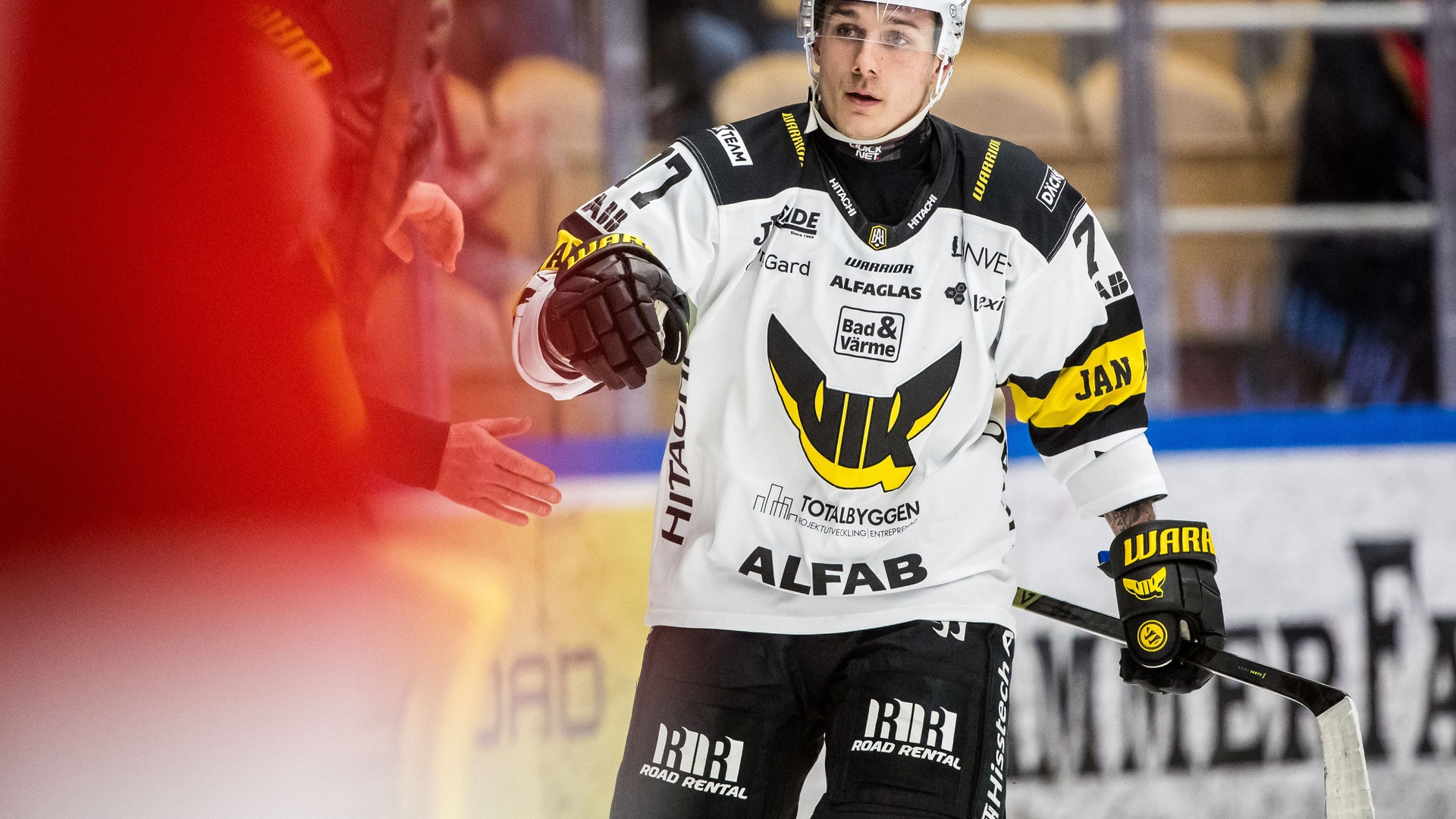 Ishockeyspelare i vit och svart matchdräkt gestikulerar under en ishockeymatch.