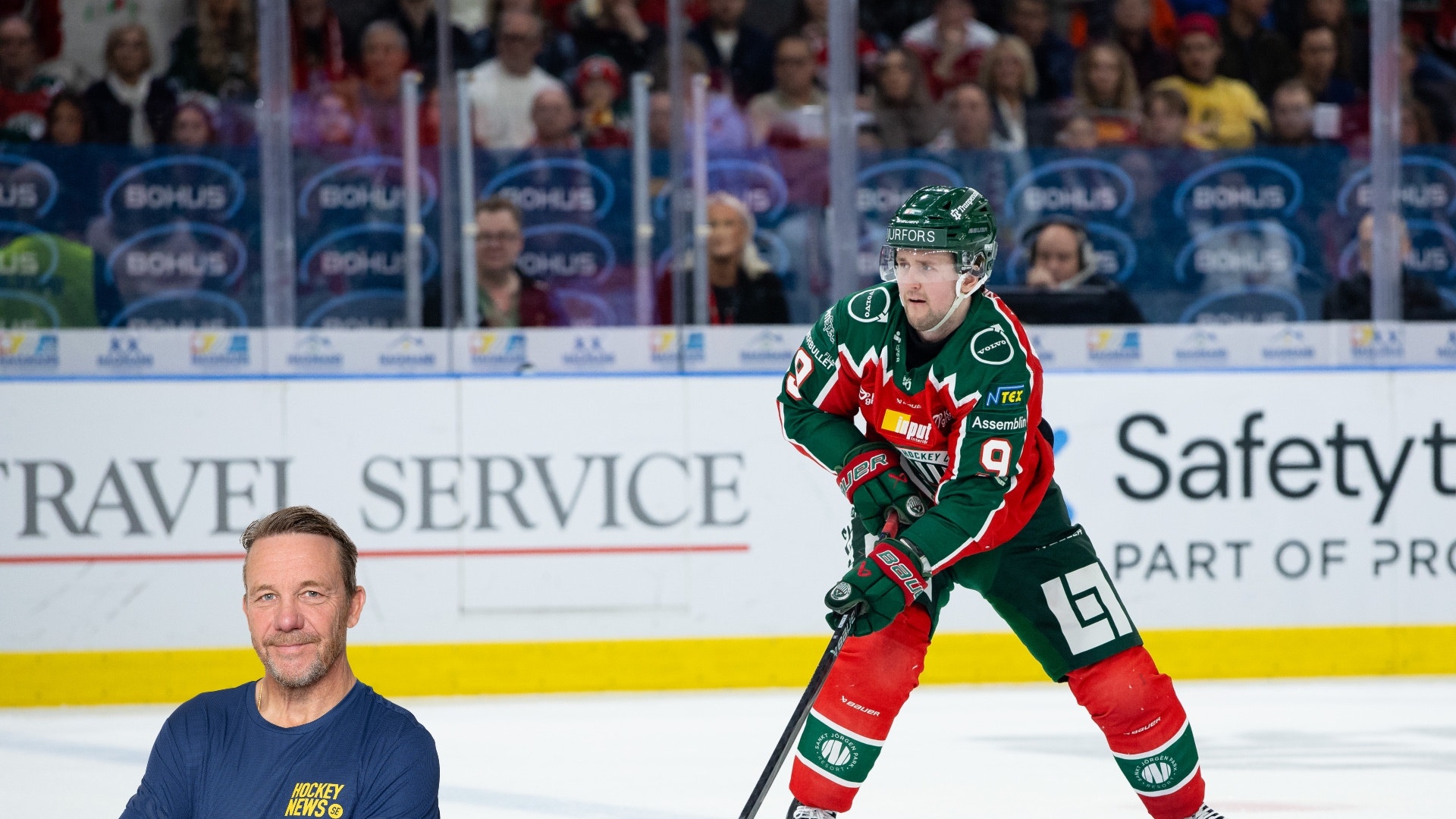 Ishockeyspelare i röd och grön tröja spelar på isen med hockey stick och puck. En man i blå t-shirt står i förgrunden. Publik syns i bakgrunden.