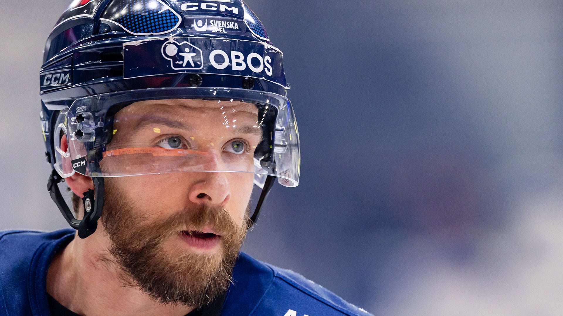 Porträtt av en ishockeyspelare med blå hjälm och skyddsmask.