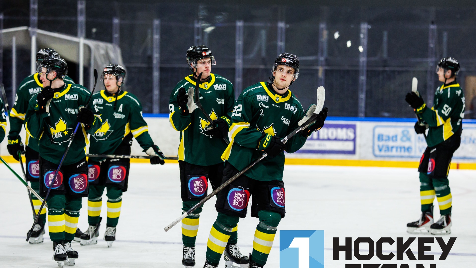 Ishockeyspelare i gröna matchtröjor åker på isen och applåderar efter en match.