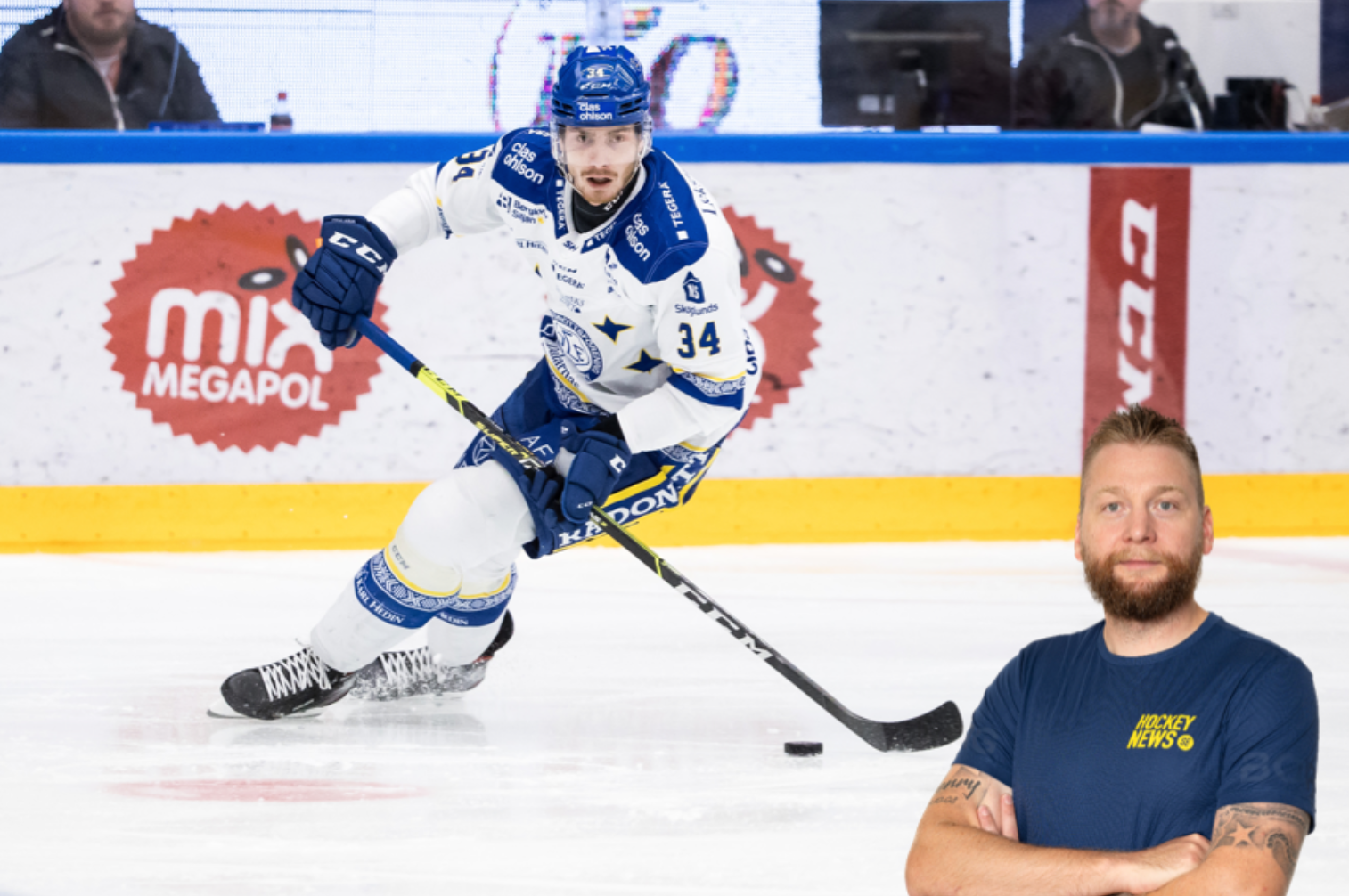 Ishockeyspelare i vit och blå uniform spelar med pucken på isen under en match.
