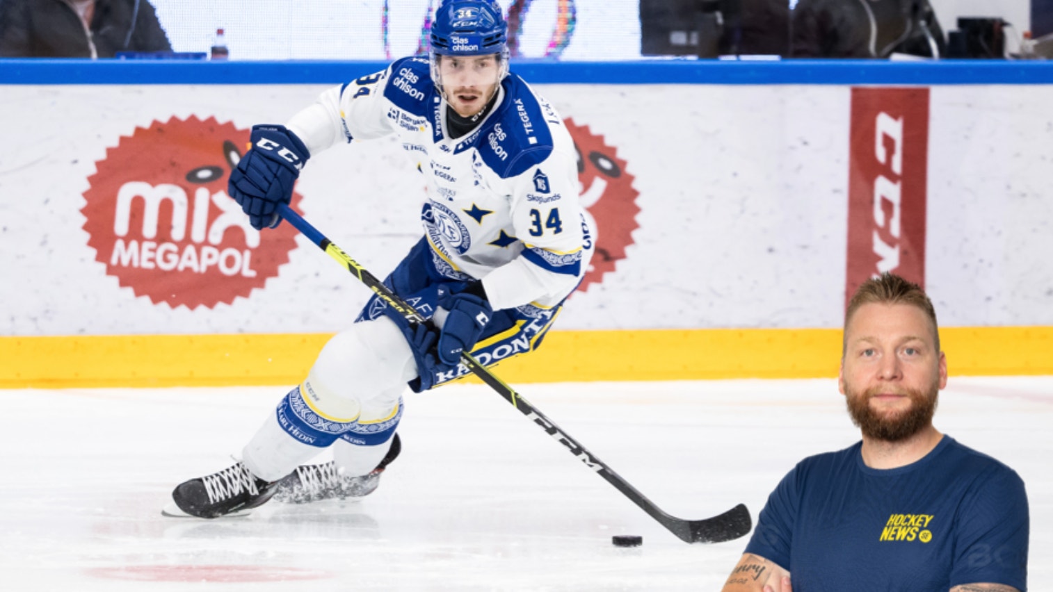 Ishockeyspelare i vit och blå uniform spelar med pucken på isen under en match.
