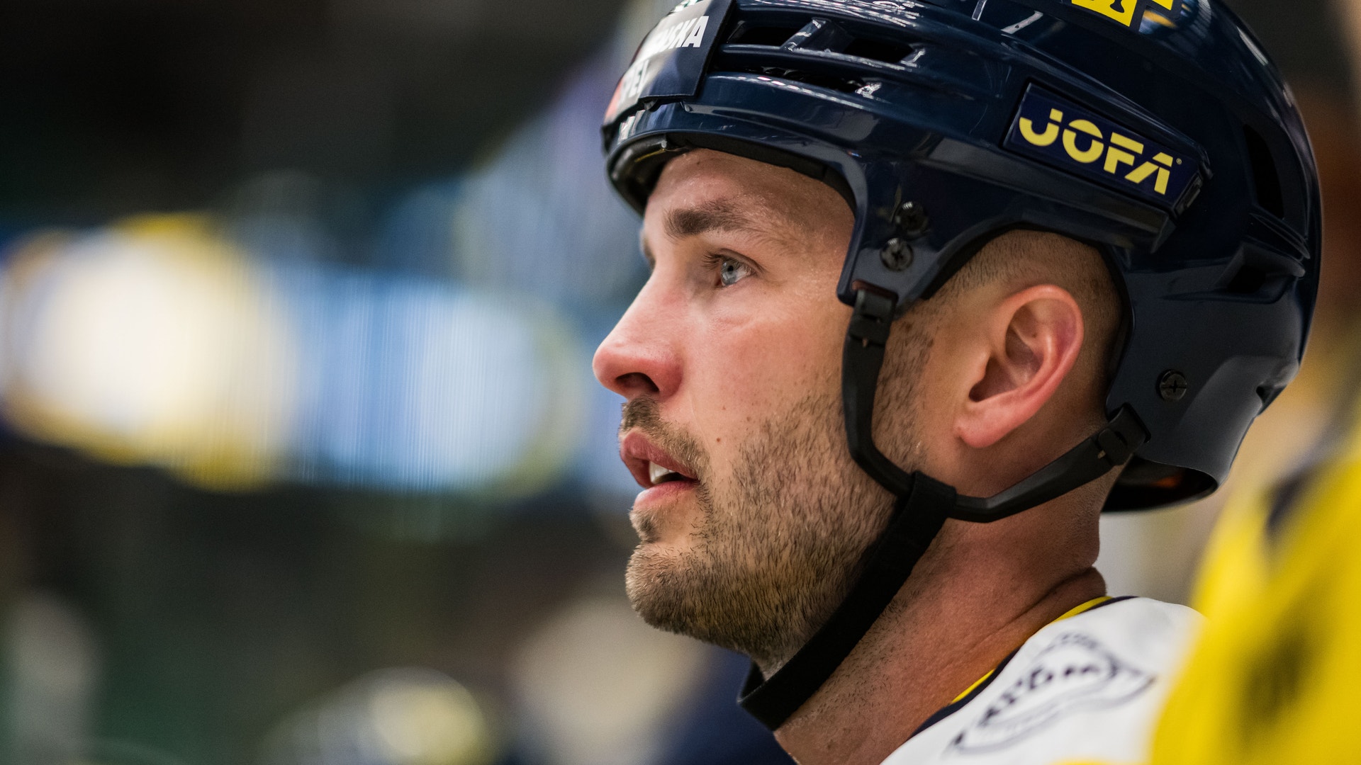 Profil av en ishockeyspelare med mörkblå hjälm under en match.