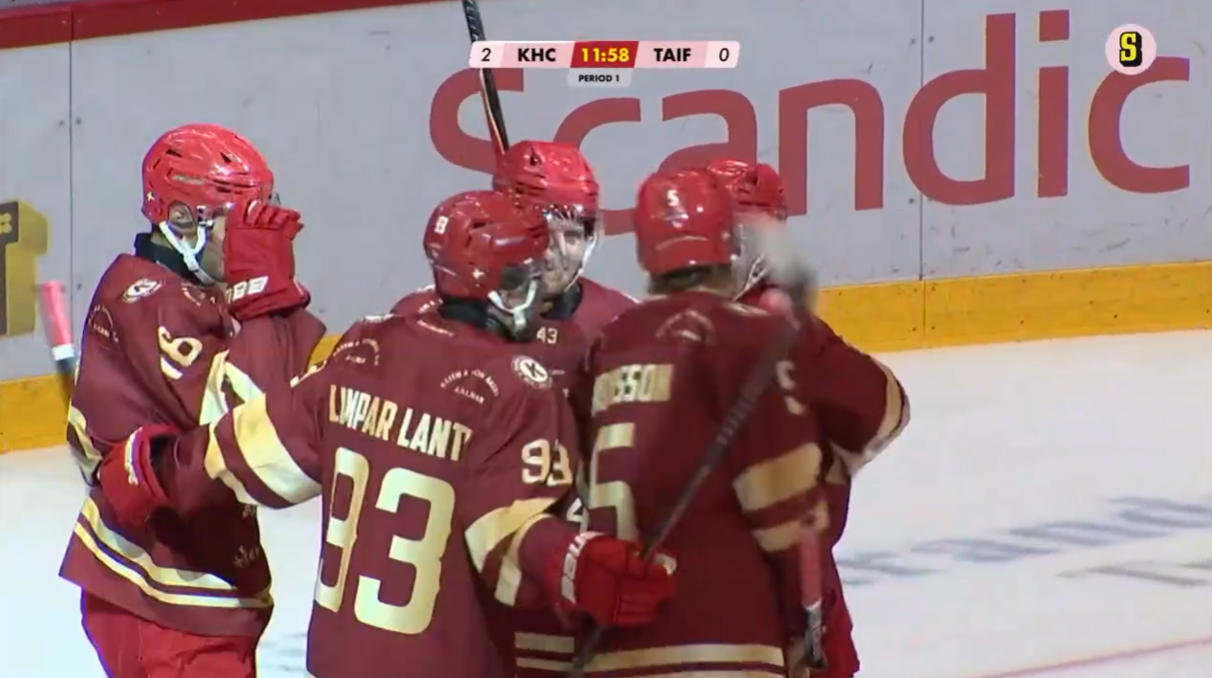 Ishockeyspelare i röda och gula tröjor samlas och firar tillsammans på isen under en match.