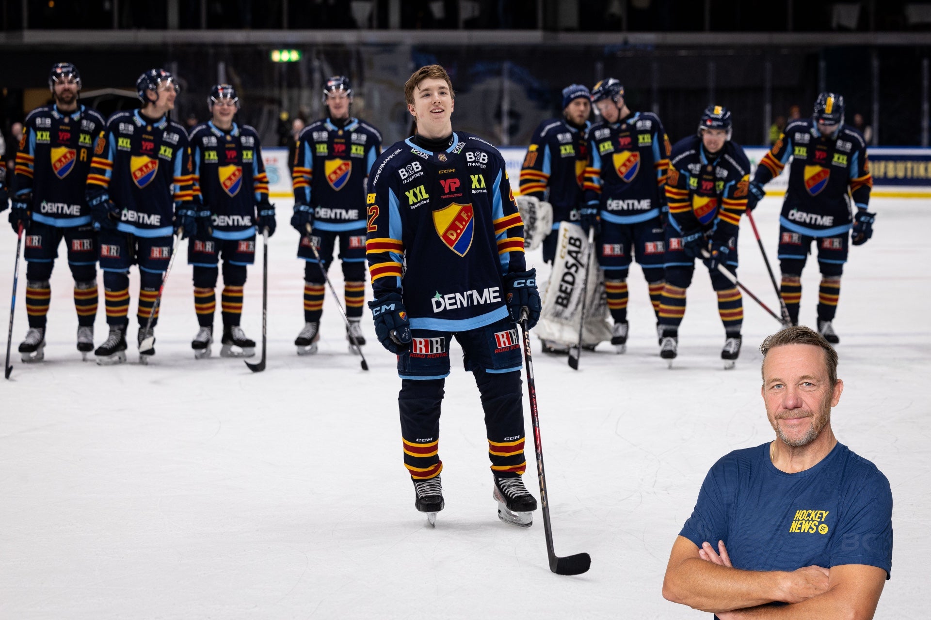 Hockeylag i svarta och gula uniformer på isen. En spelare står framför laget med en hockeyklubb, medan övriga lagkamrater står bakom honom. I förgrunden till höger syns en man i blå t-shirt som poserar för kameran.