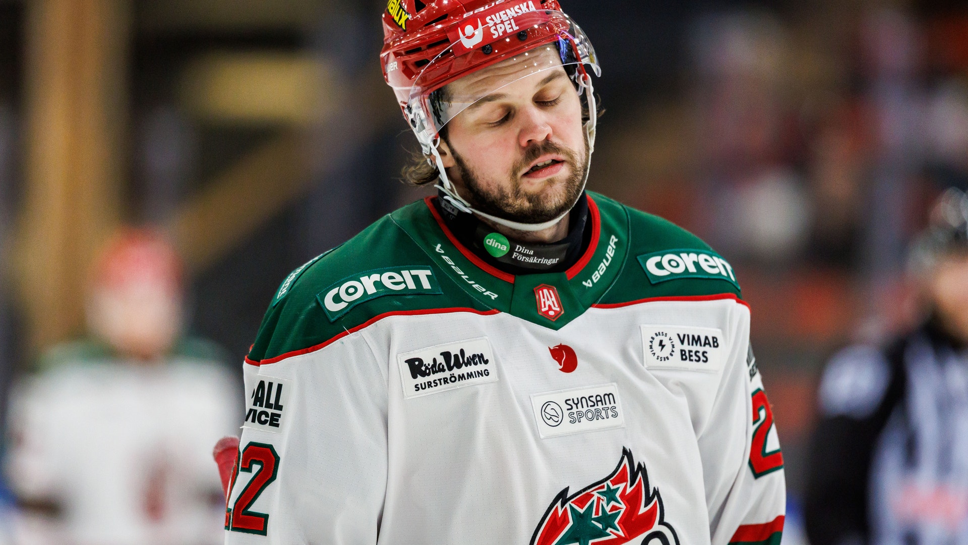 Ishockeyspelare i röd hjälm och röd-vit tröja under en match.