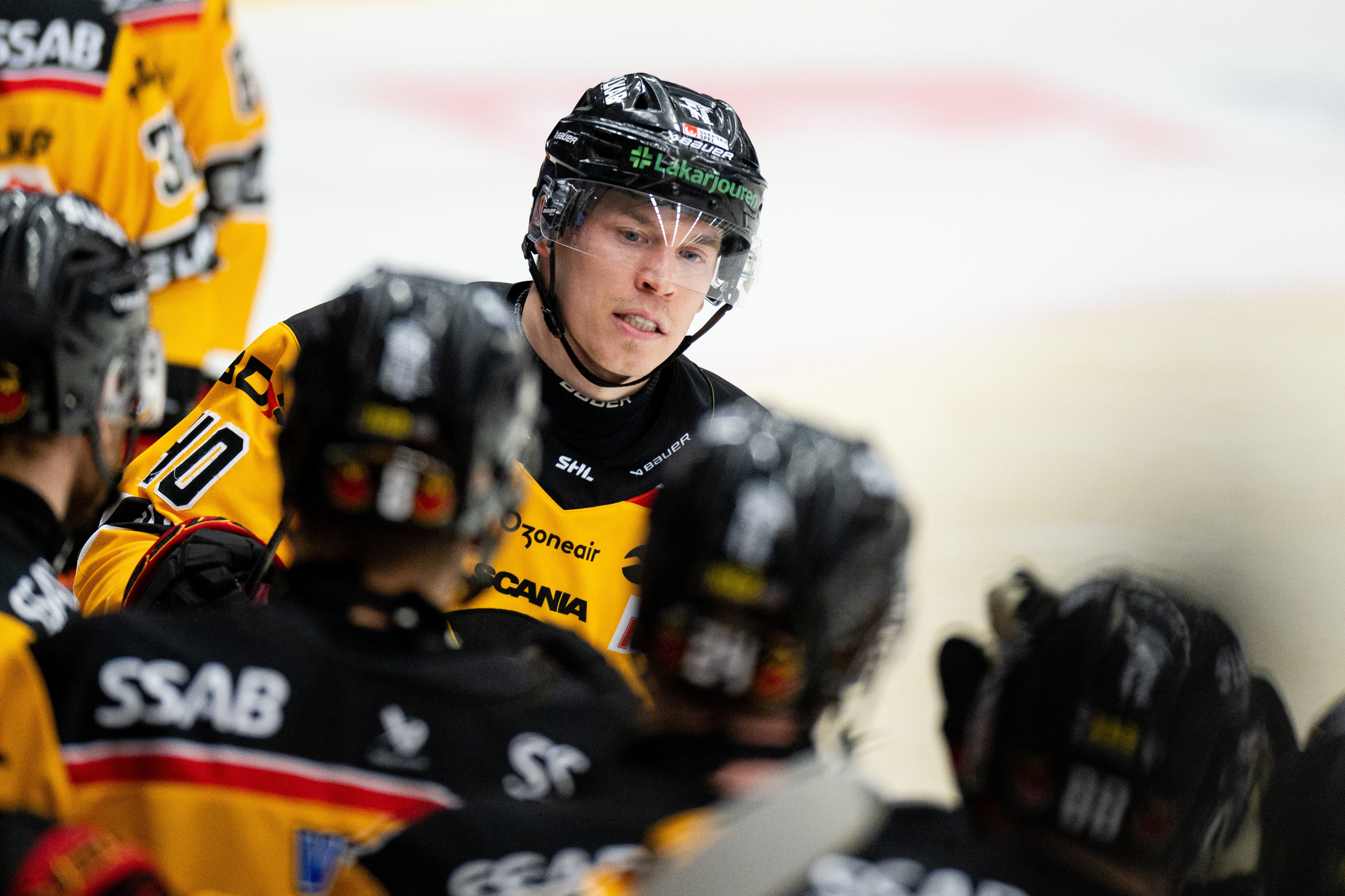 Ishockeyspelare i gul och svart uniform med hjälm under en match.