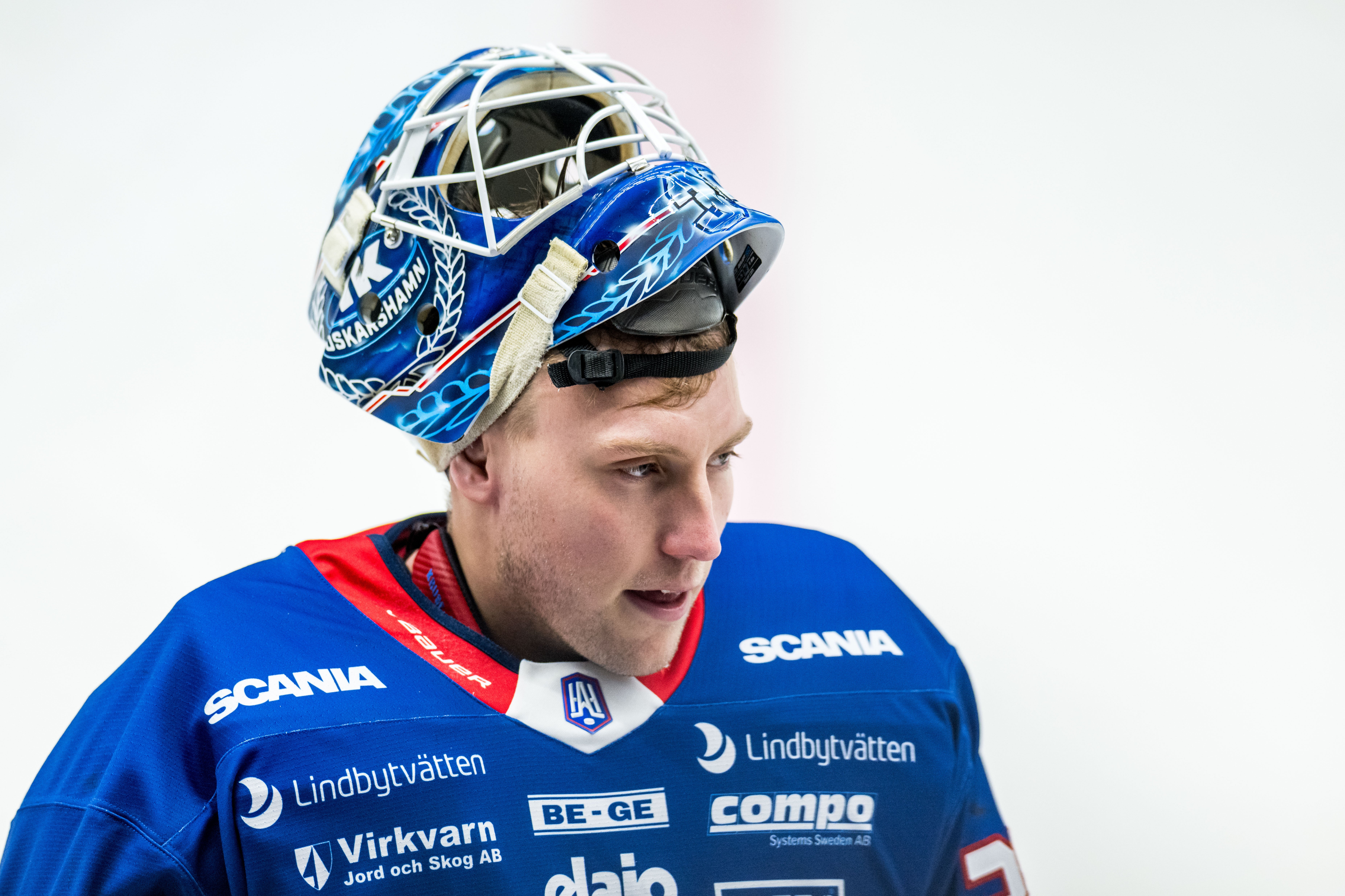 Ishockeyspelare i blå uniform och målvaktsmask med blå och vita mönster.