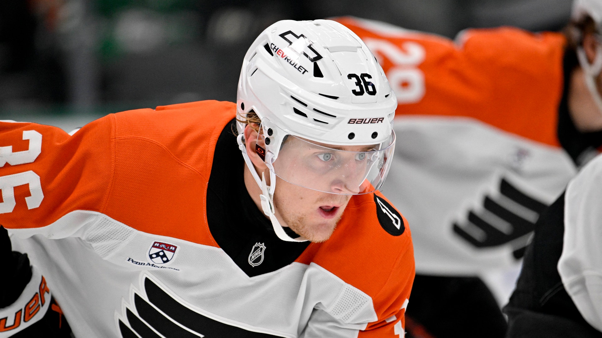 Ishockeyspelare i orange och vit tröja med nummer 36 och vit hjälm under en match.