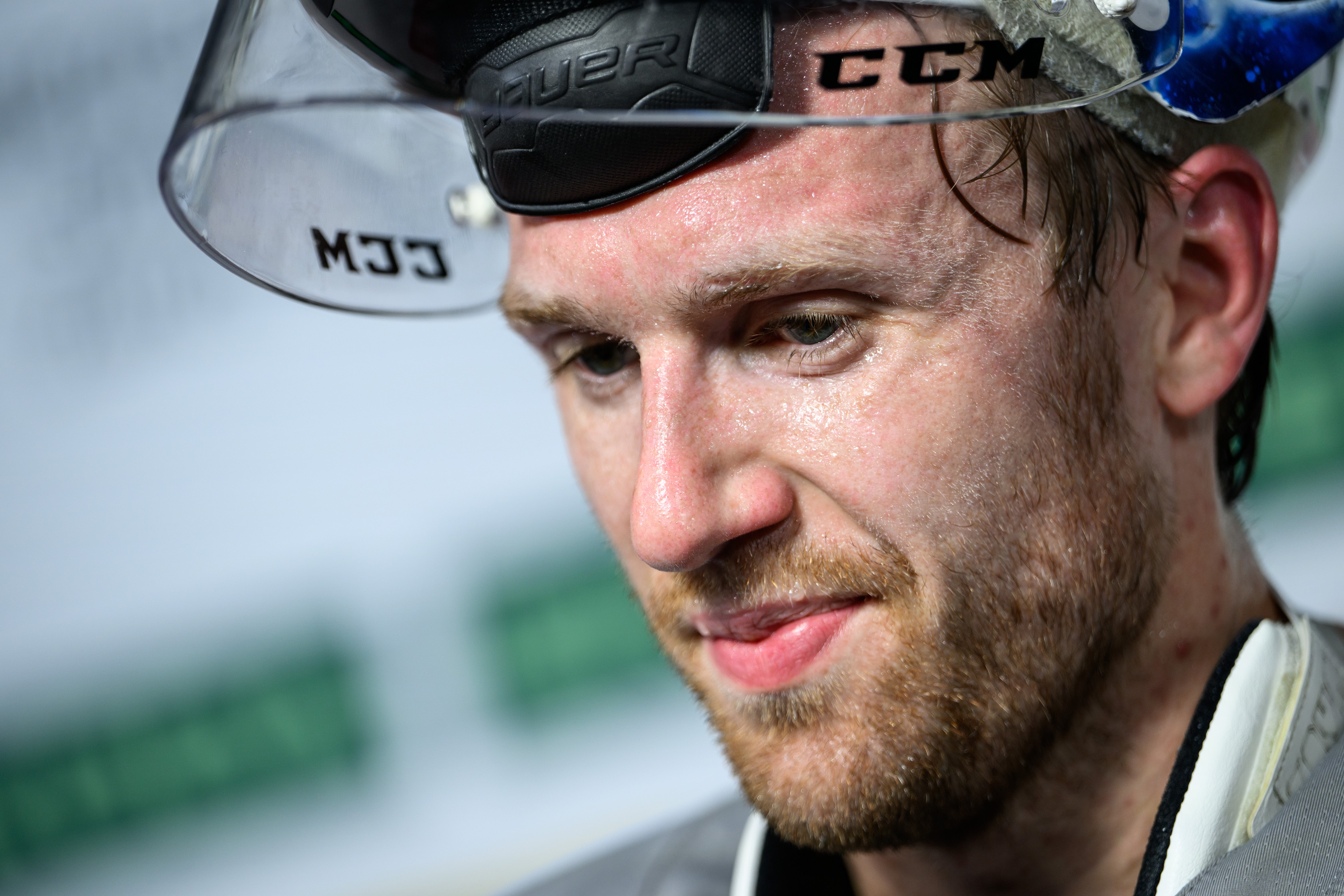 Ishockeyspelare firar på isen med upphöjd arm och hockeyklubbe. Spelaren bär svart och vit tröja med röda detaljer. Publik syns på läktaren i bakgrunden.