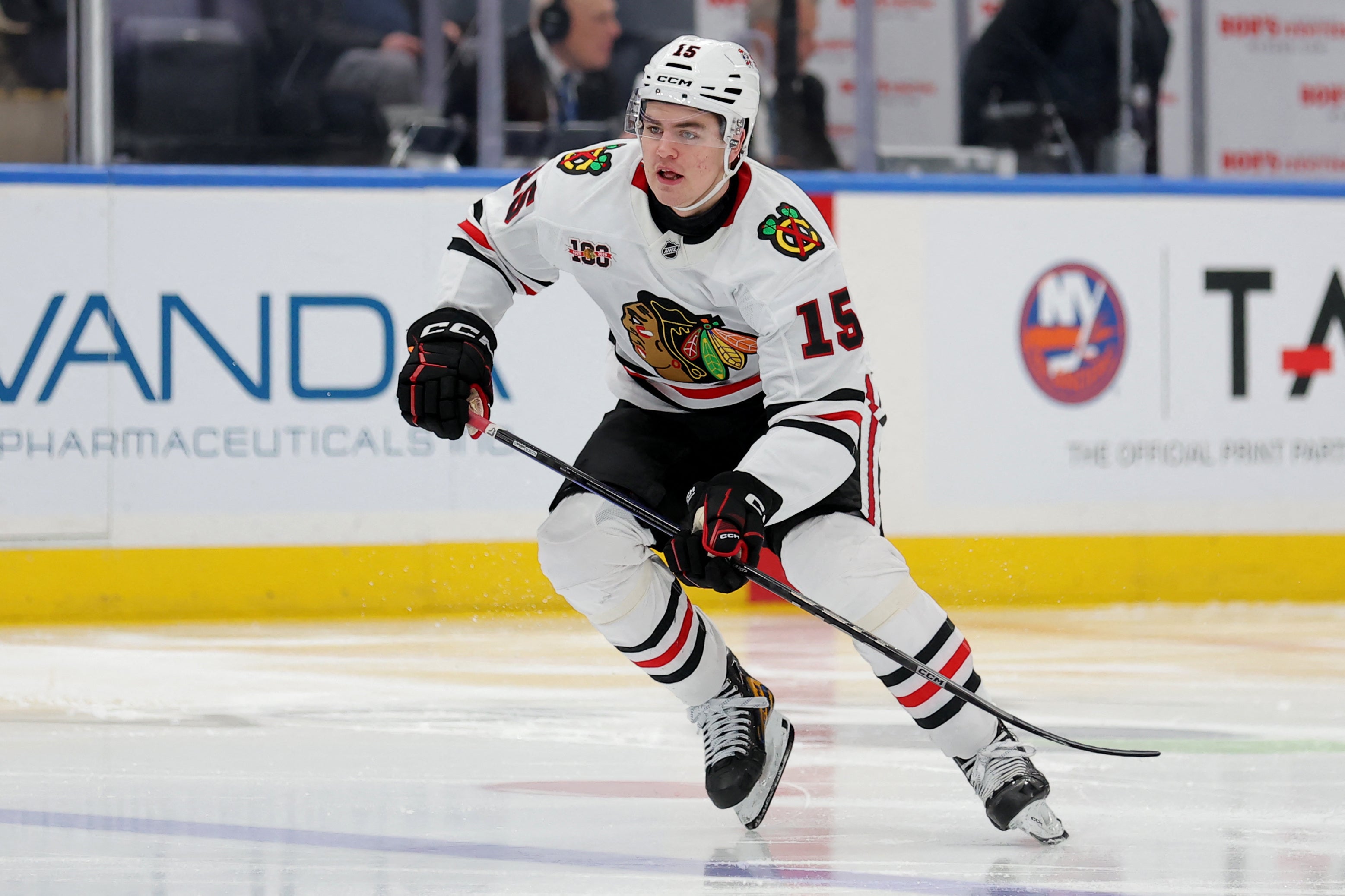Ishockeyspelare i vit Chicago Blackhawks-tröja med nummer 18 spelar på isen under en match.