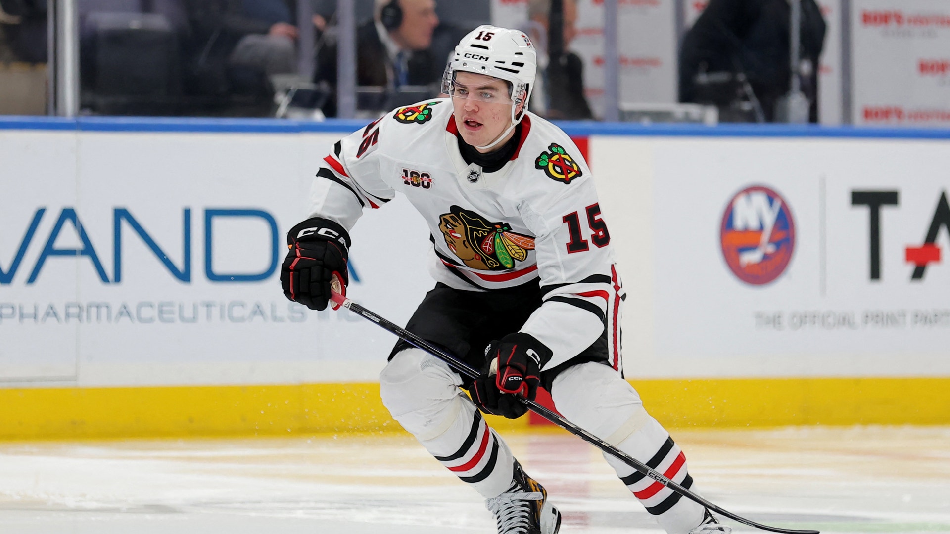 Ishockeyspelare i vit Chicago Blackhawks-tröja med nummer 18 spelar på isen under en match.