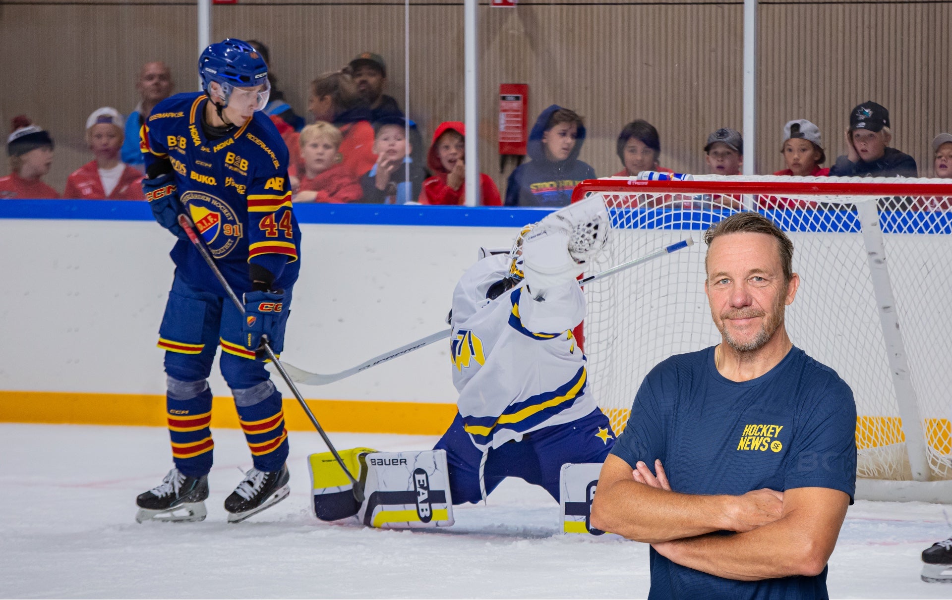 Man i mörkblå Hockey News-tröja står framför en ishockeyrink med spelare och publik i bakgrunden.