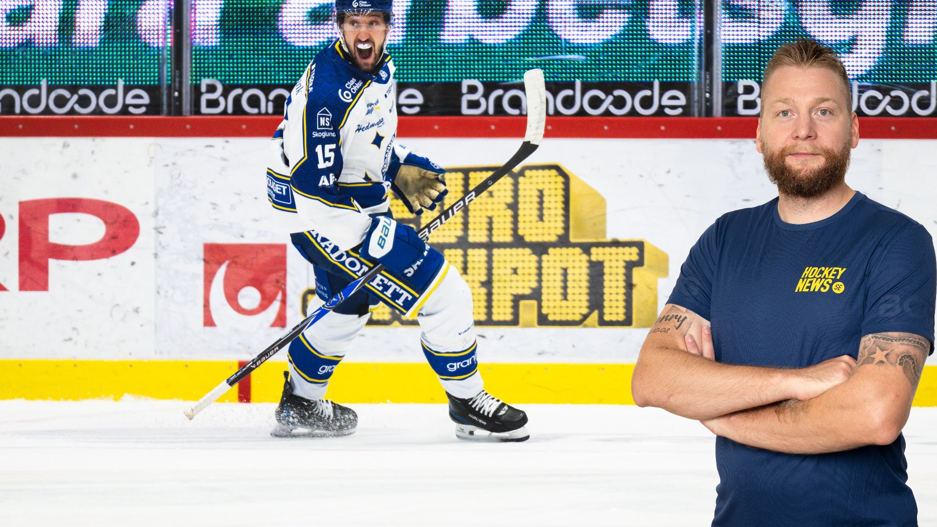 En hockeyspelare i blå och vit tröja på isen vid banden, tillsammans med en man i mörkblå t-shirt som står framför en sponsorvägg.