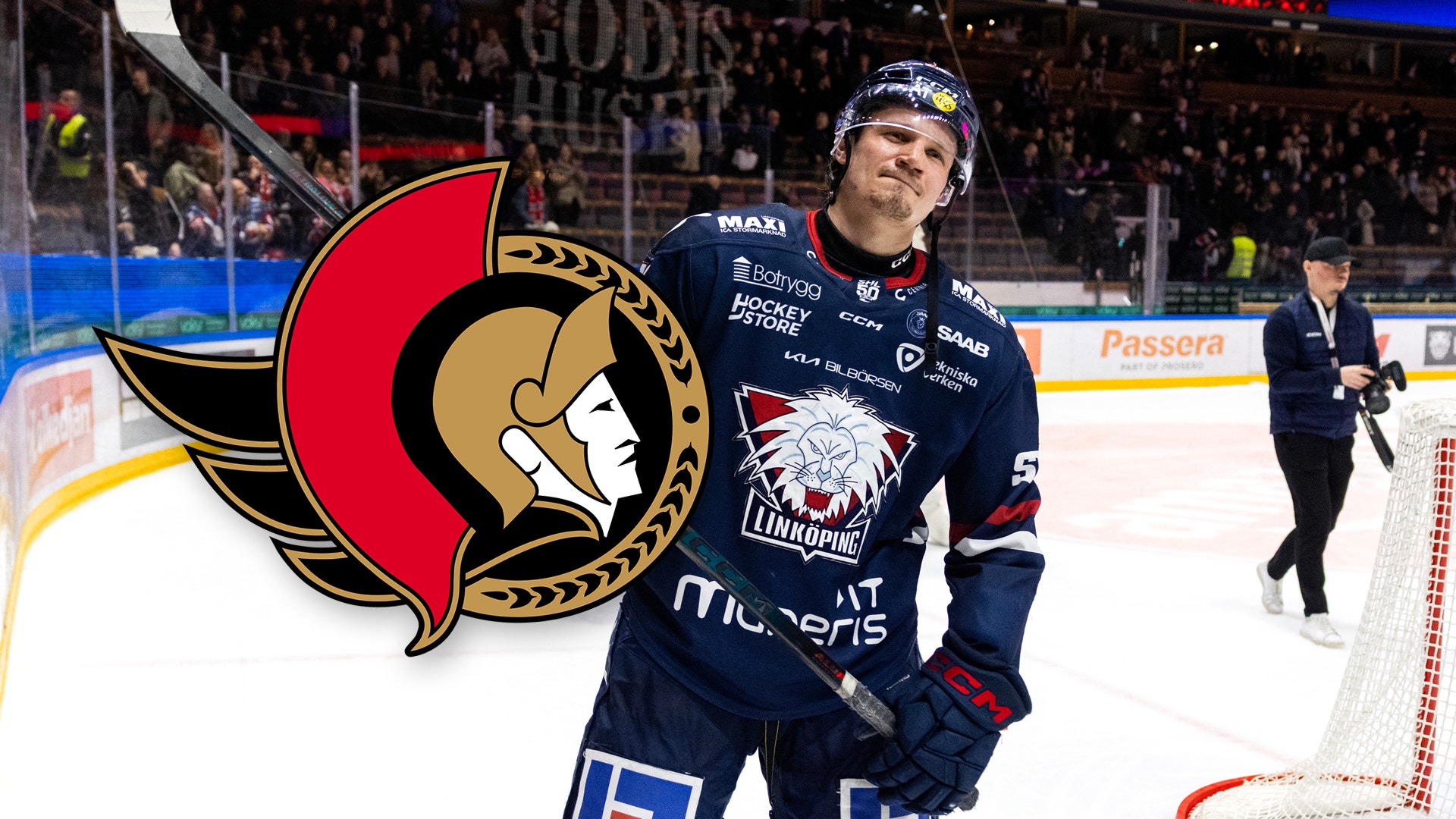 Ishockeyspelare i mörkblå tröja står på ishockeyplanen med publiken i bakgrunden.