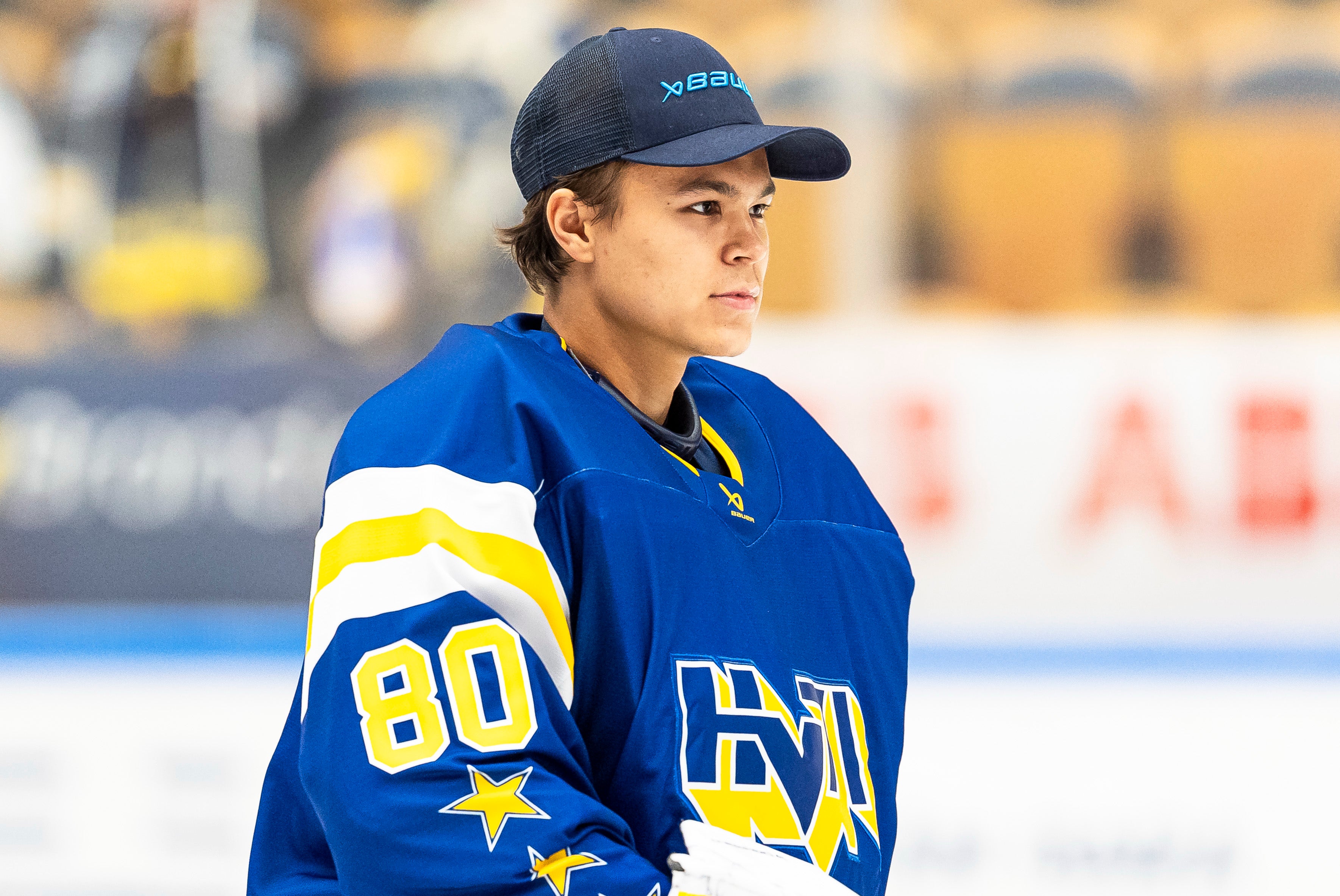 Ung ishockeyspelare i blå tröja med nummer 80 på en ishockeyrink