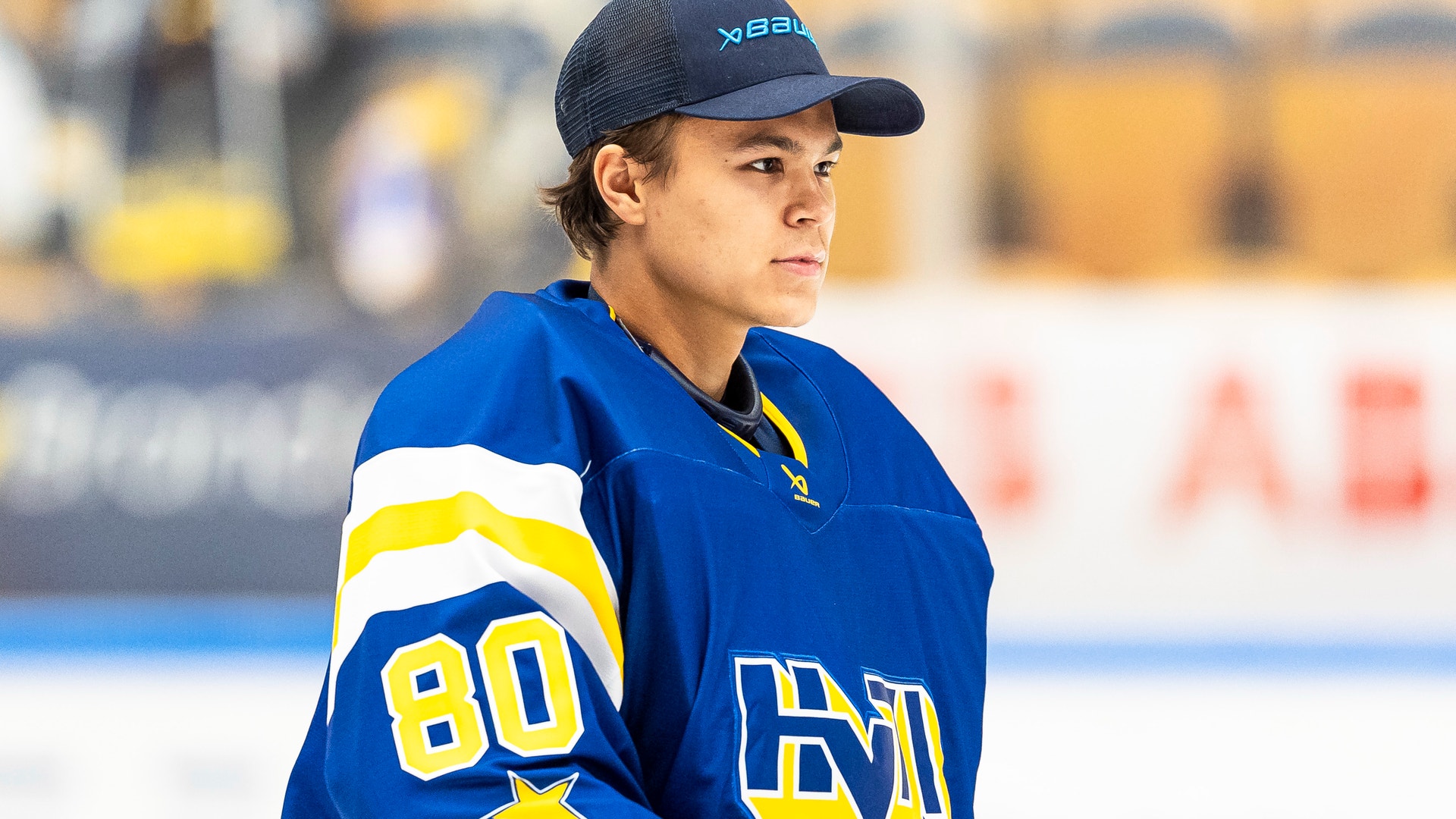 Ung ishockeyspelare i blå tröja med nummer 80 på en ishockeyrink