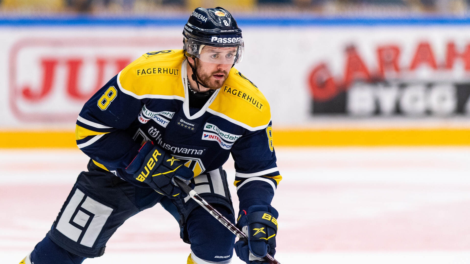Ishockeyspelar i mörkblå och gul tröja spelar på isen under en match.