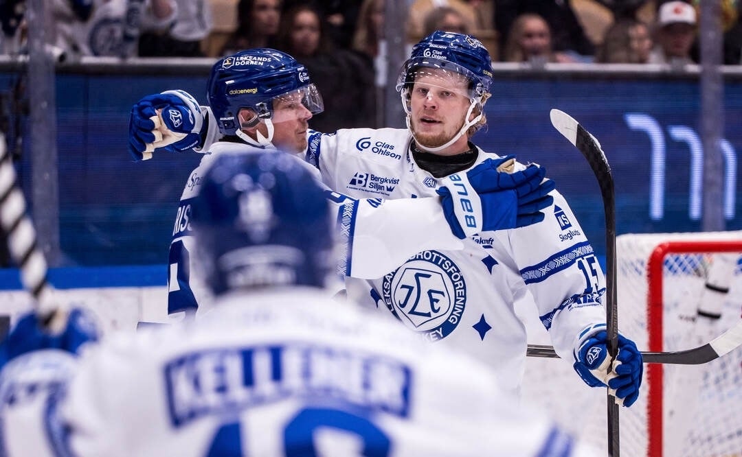 Ishockeyspelare i vita matchtröjor jublar tillsammans på isen.