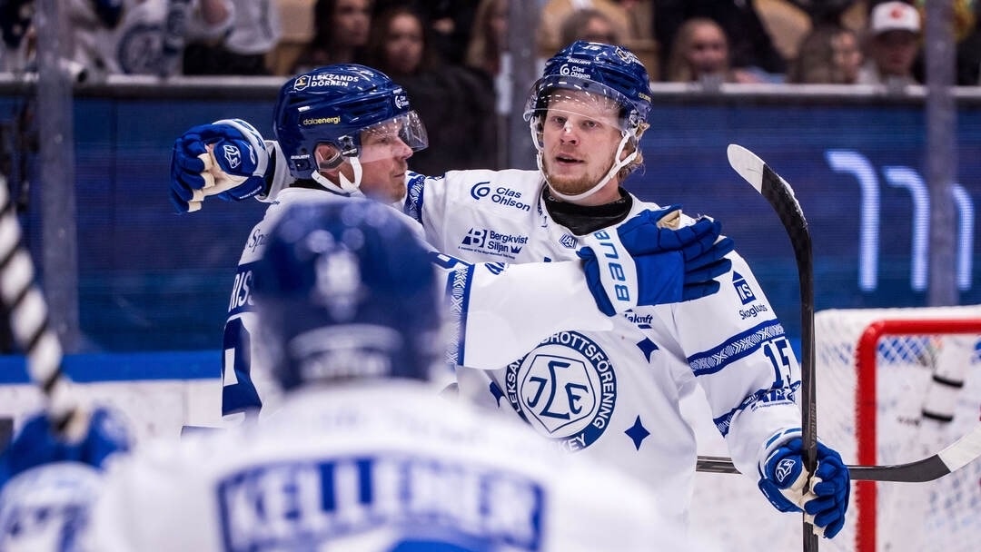 Ishockeyspelare i vita matchtröjor jublar tillsammans på isen.