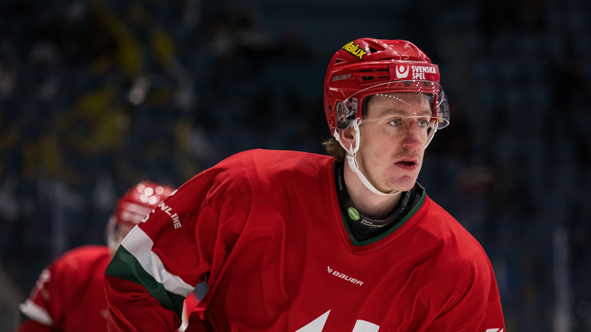 Ishockeyspelare i röd tröja och röd hjälm under en match.