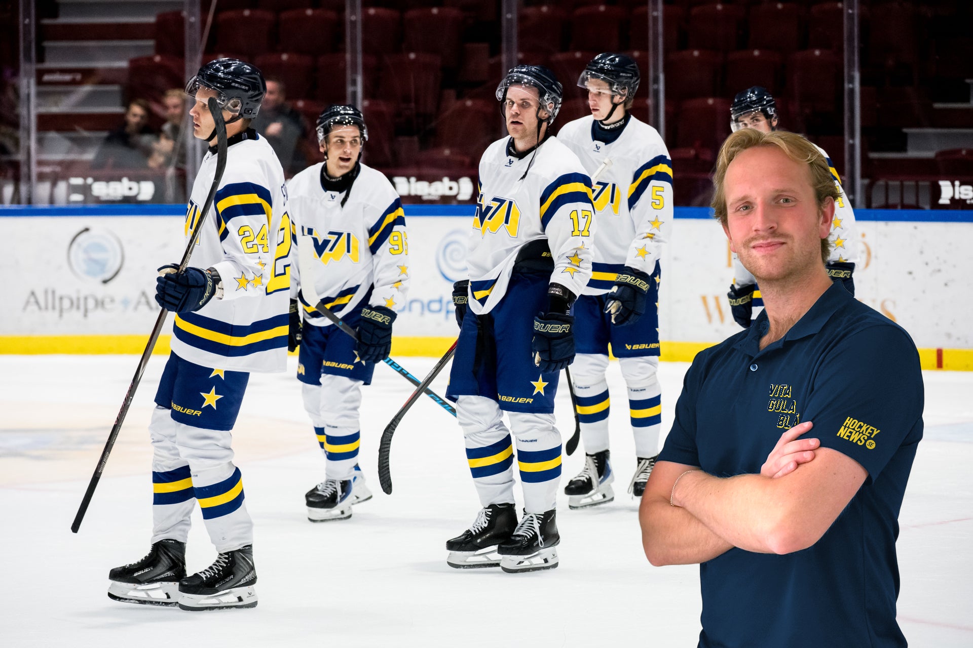 En ishockeytränare står framför sitt lag på isen under en match eller träning.