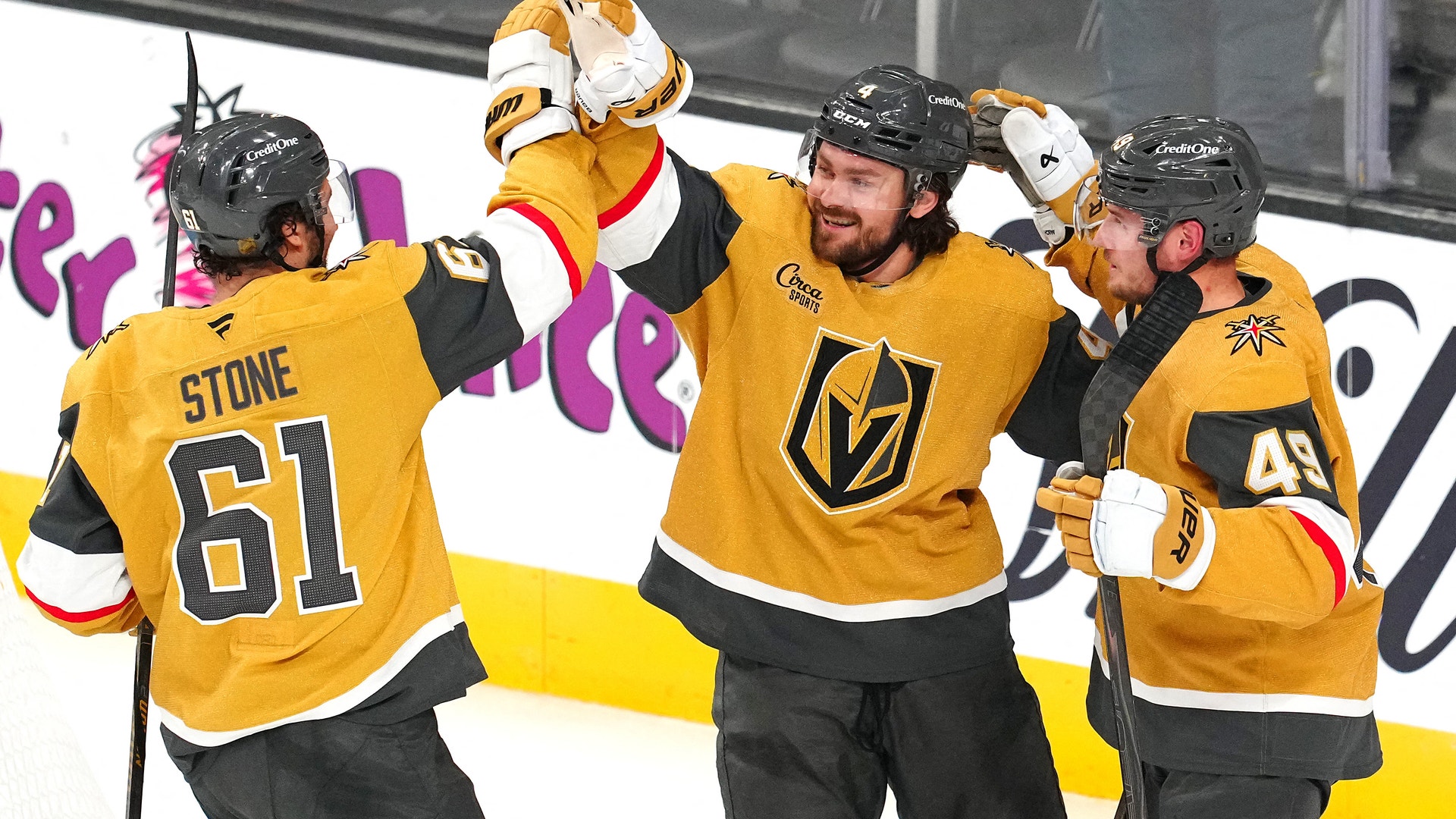 Ishockeyspelare i gula och svarta trikåer jublar tillsammans under en match, med upphöjda händer och stick.