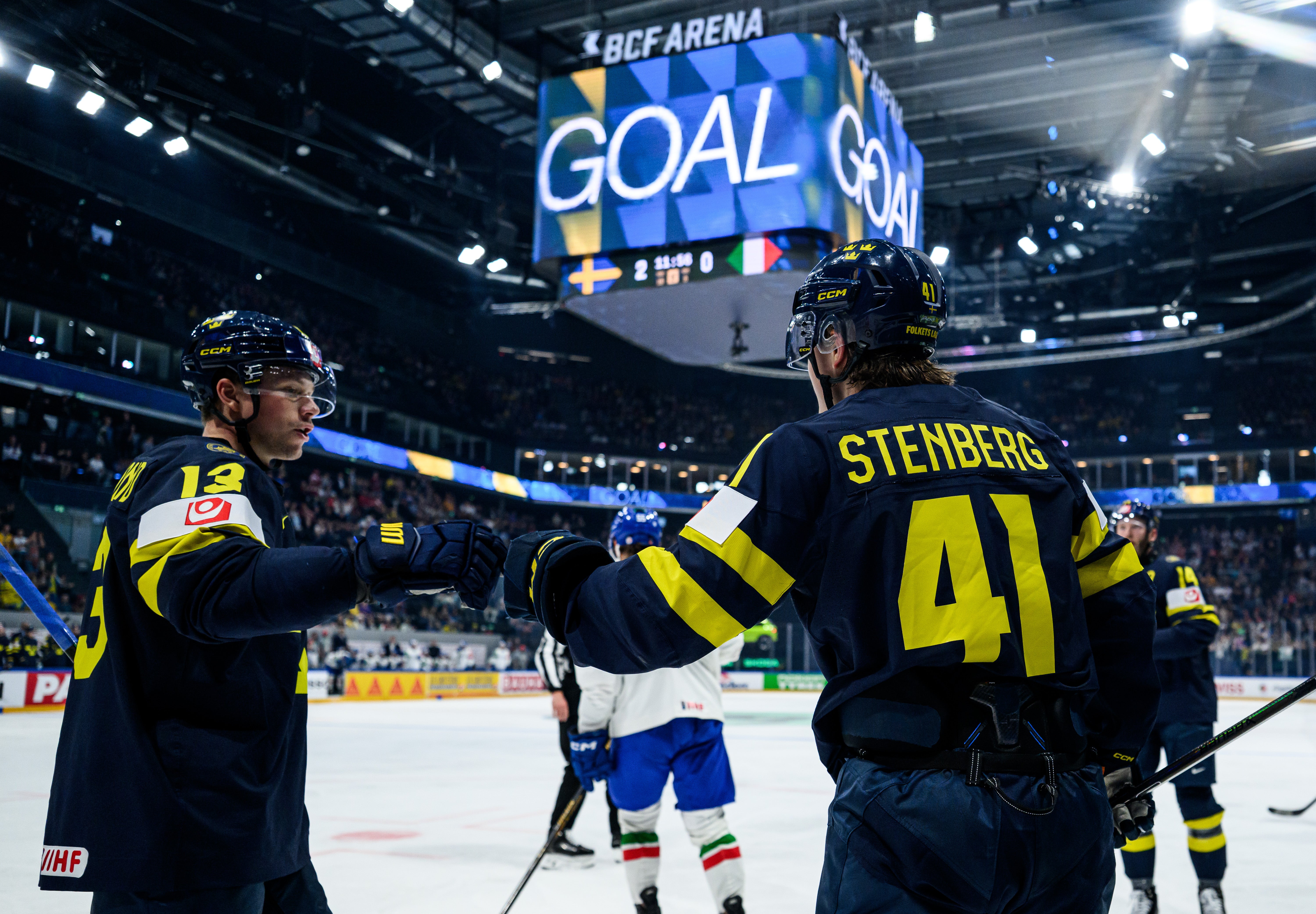 Ishockeyspelare i vit och grön matchdräkt under en ishockeymatch.