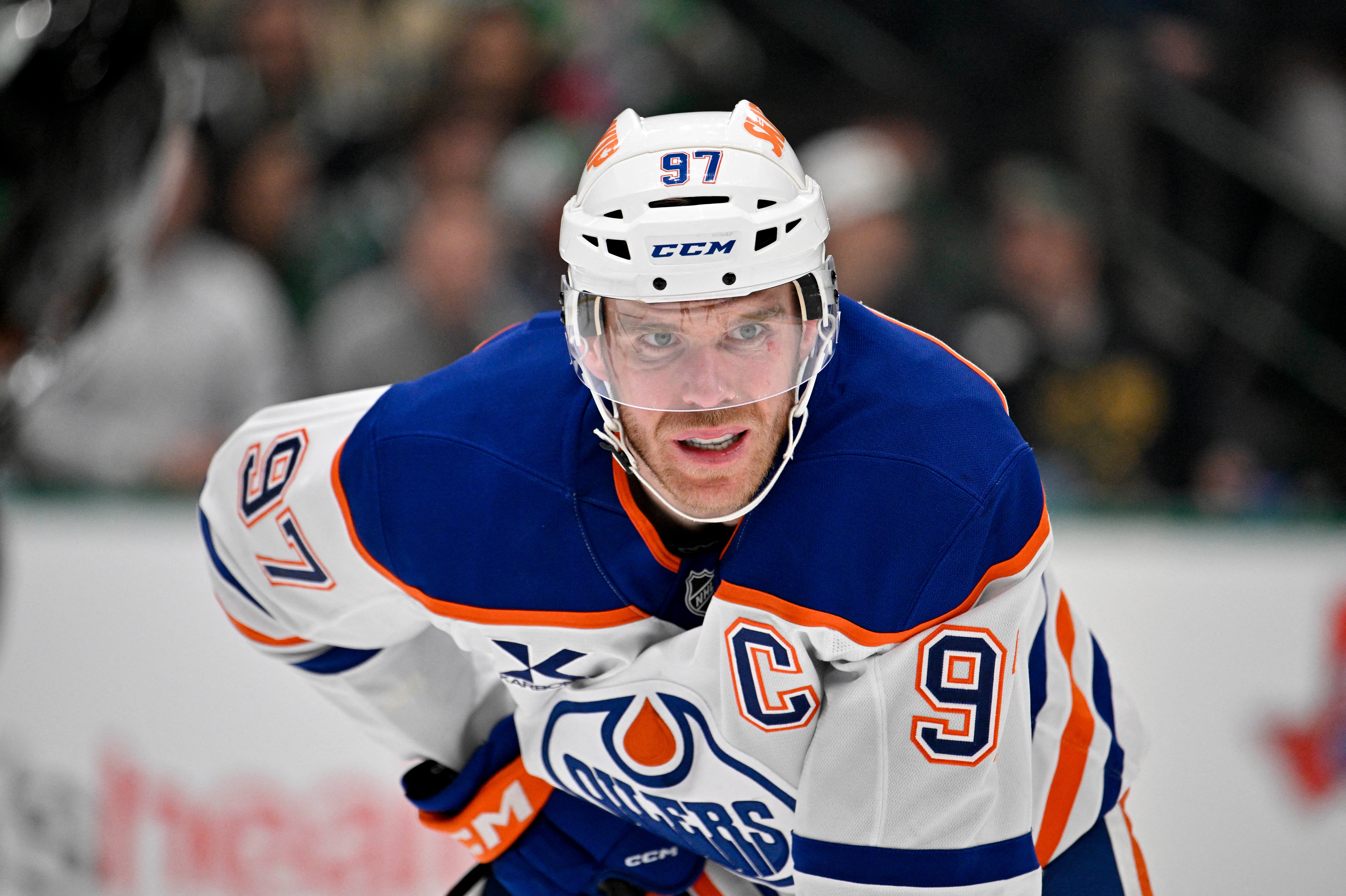 Ishockeyspelare i blå och vit Edmonton Oilers-tröja med nummer 97 och lagkaptensbindel, fotograferad under en match.
