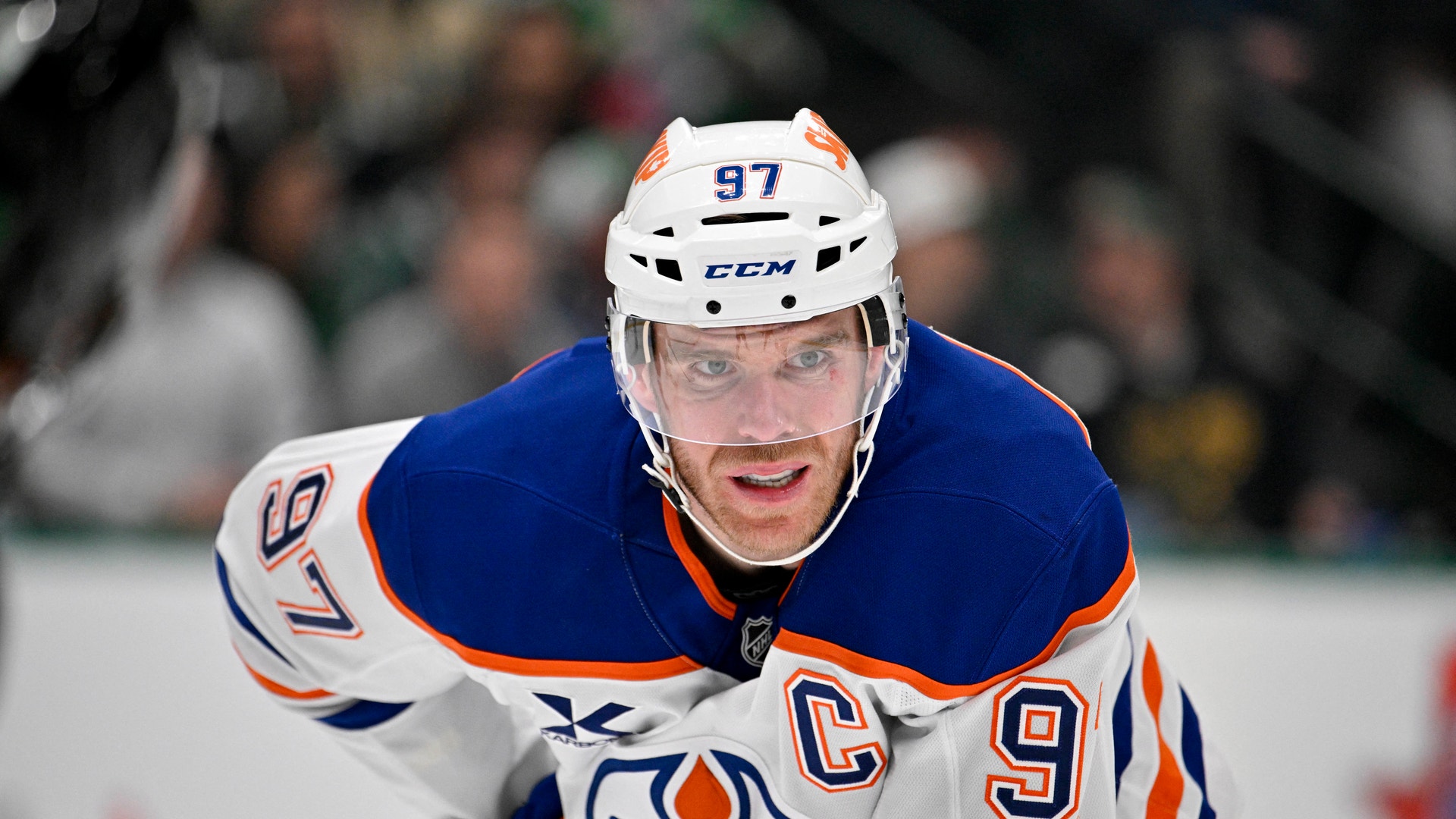 Ishockeyspelare i blå och vit Edmonton Oilers-tröja med nummer 97 och lagkaptensbindel, fotograferad under en match.