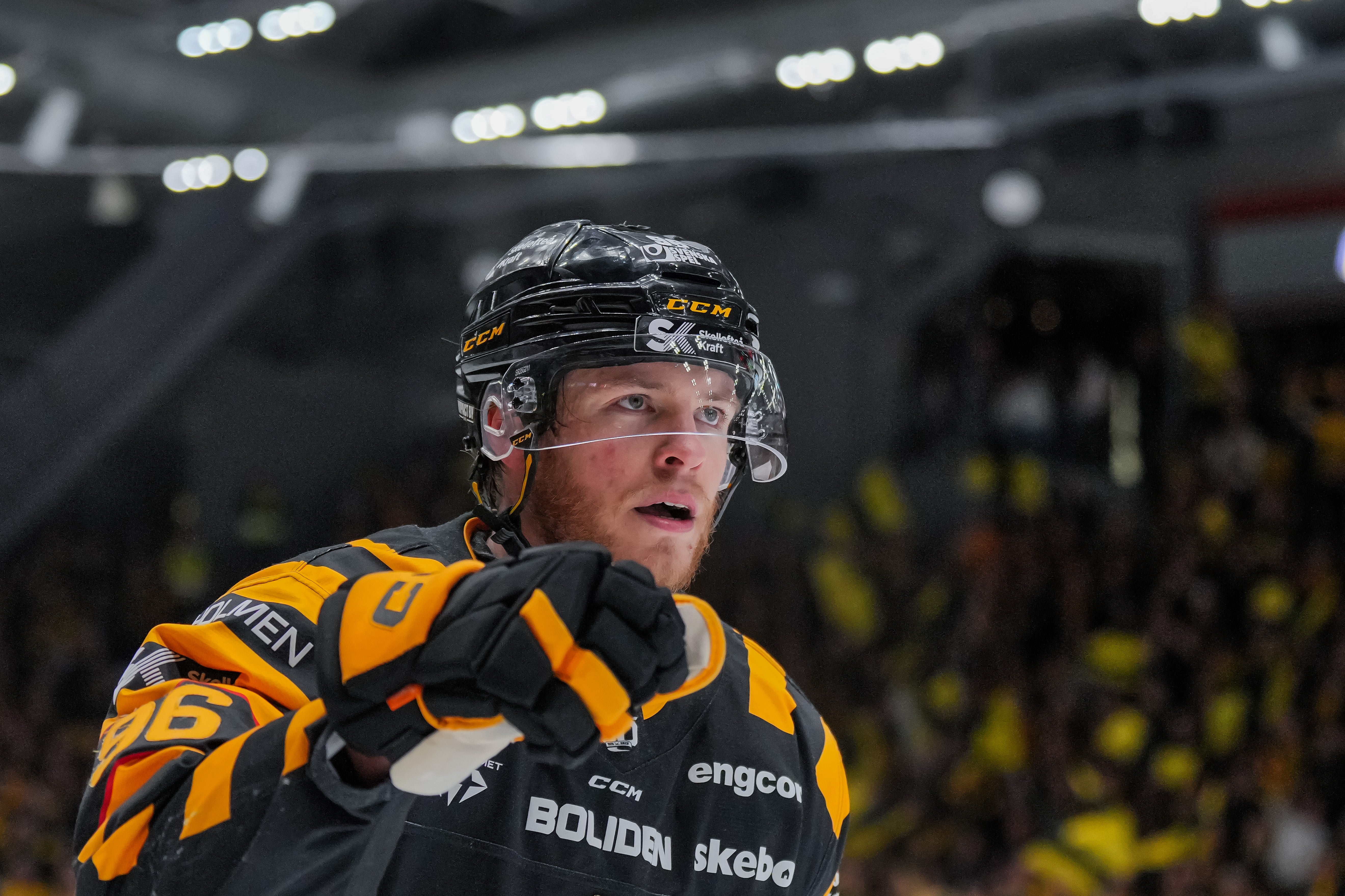 En ishockeyspelare i gul och svart uniform med hjälm under en match i en ishall.