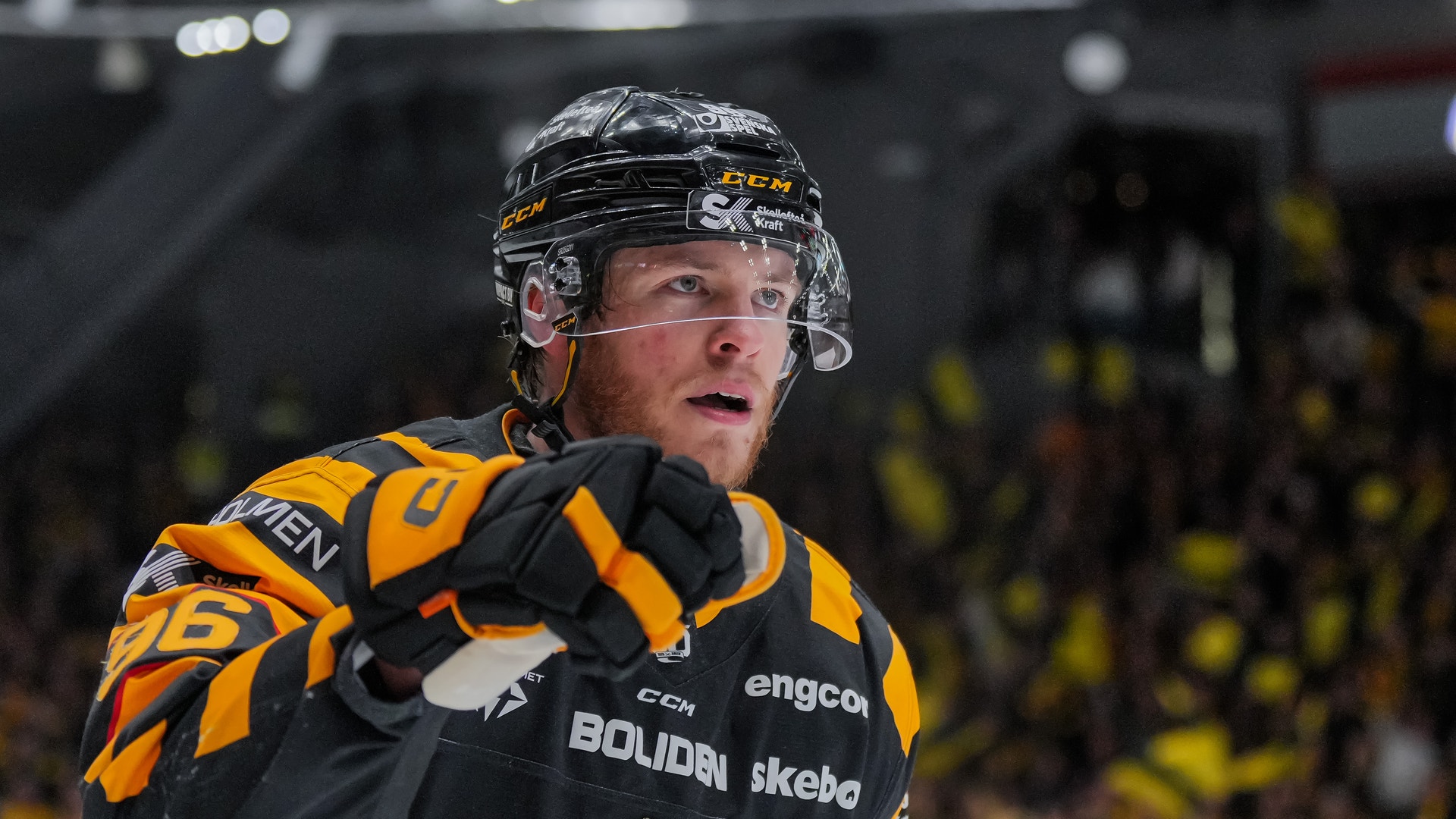 En ishockeyspelare i gul och svart uniform med hjälm under en match i en ishall.