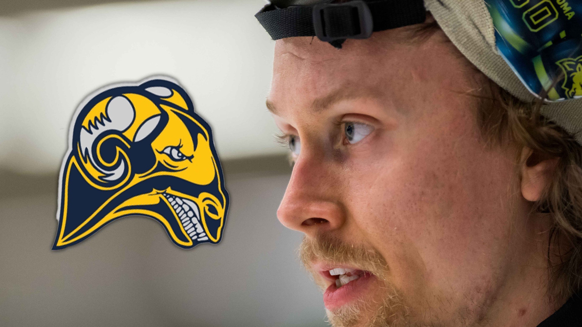 Porträtt av en man i profil som bär en sportmössa. En gul och blå laglogotyp föreställande en hjälm är överlagd på bilden.