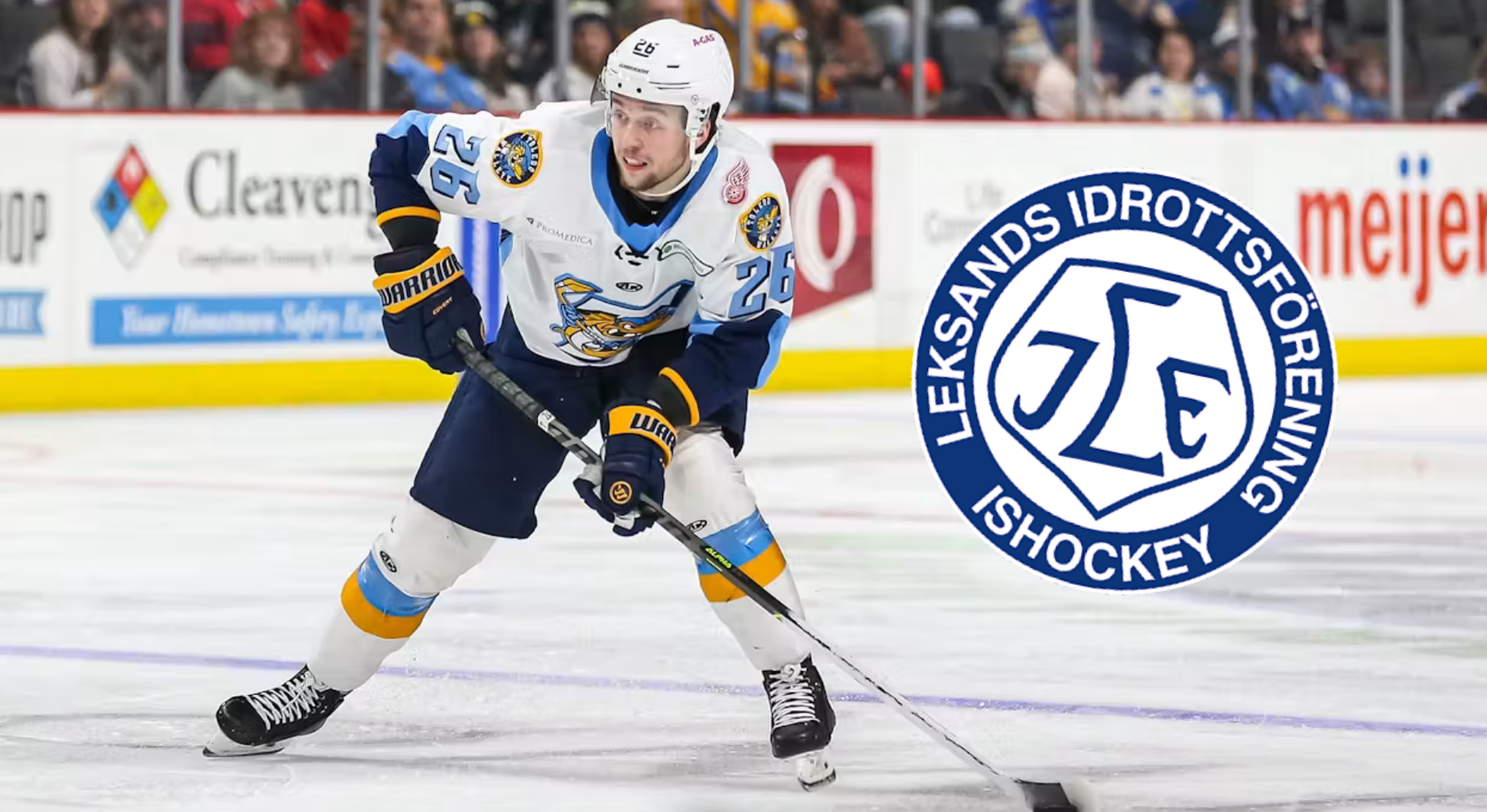 Ishockeyspelare i mörkblå och vit uniform med gula detaljer dribblar med pucken på isen under en match. Leksands Idrottsförenings logga är synlig i bilden.