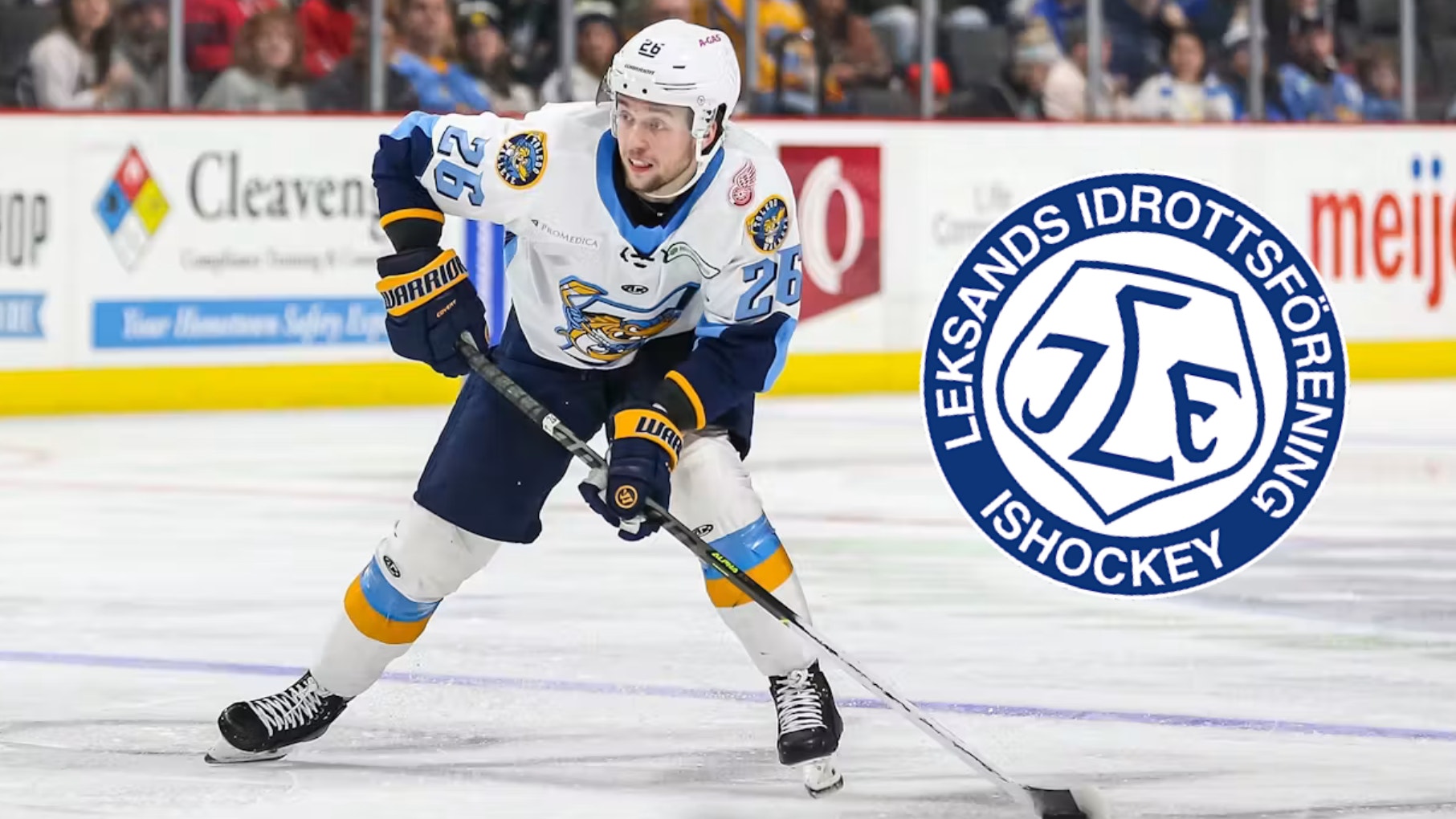 Ishockeyspelare i mörkblå och vit uniform med gula detaljer dribblar med pucken på isen under en match. Leksands Idrottsförenings logga är synlig i bilden.