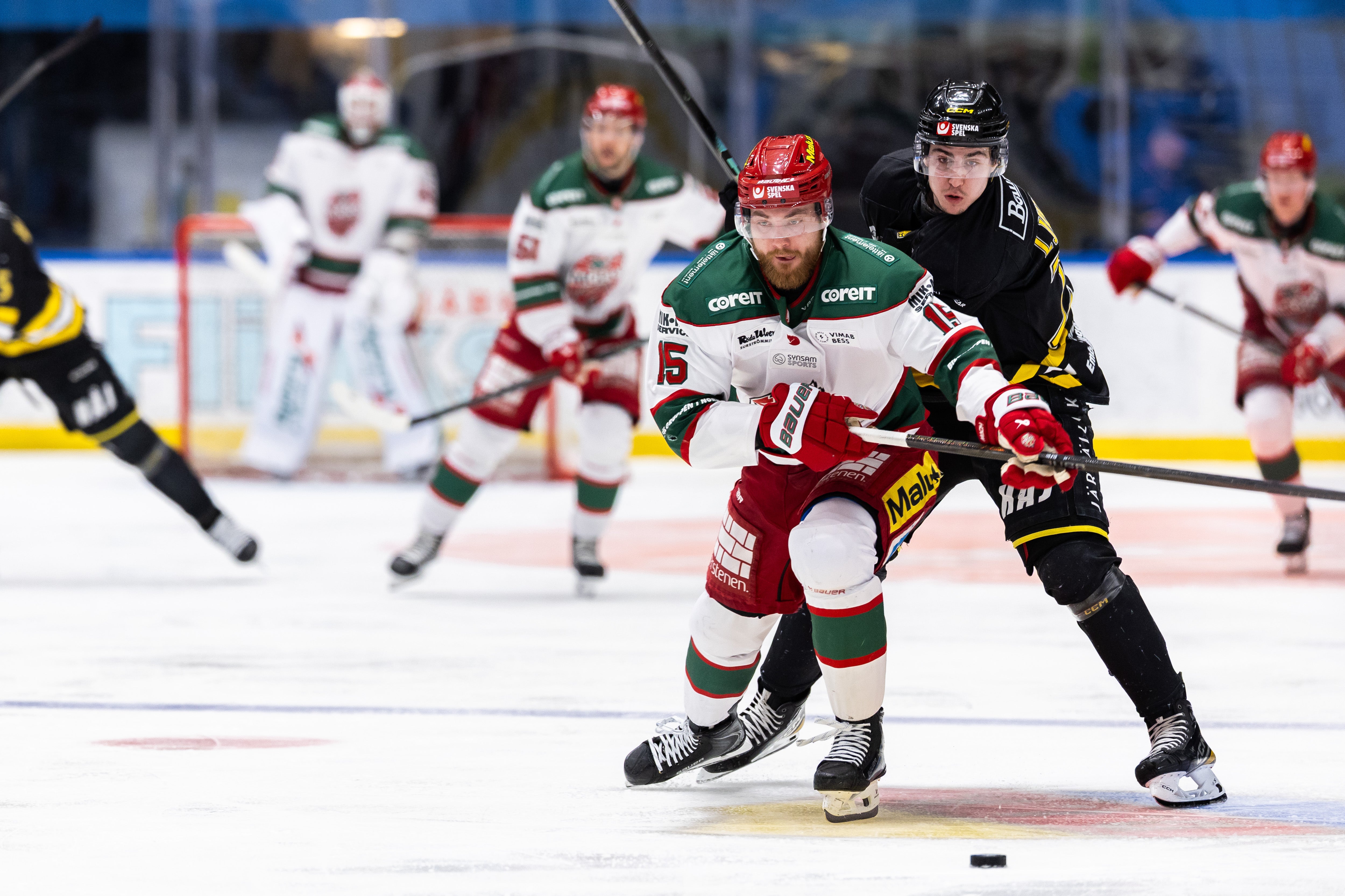 Ishockeyspelare från två lag kämpar om pucken under en match.