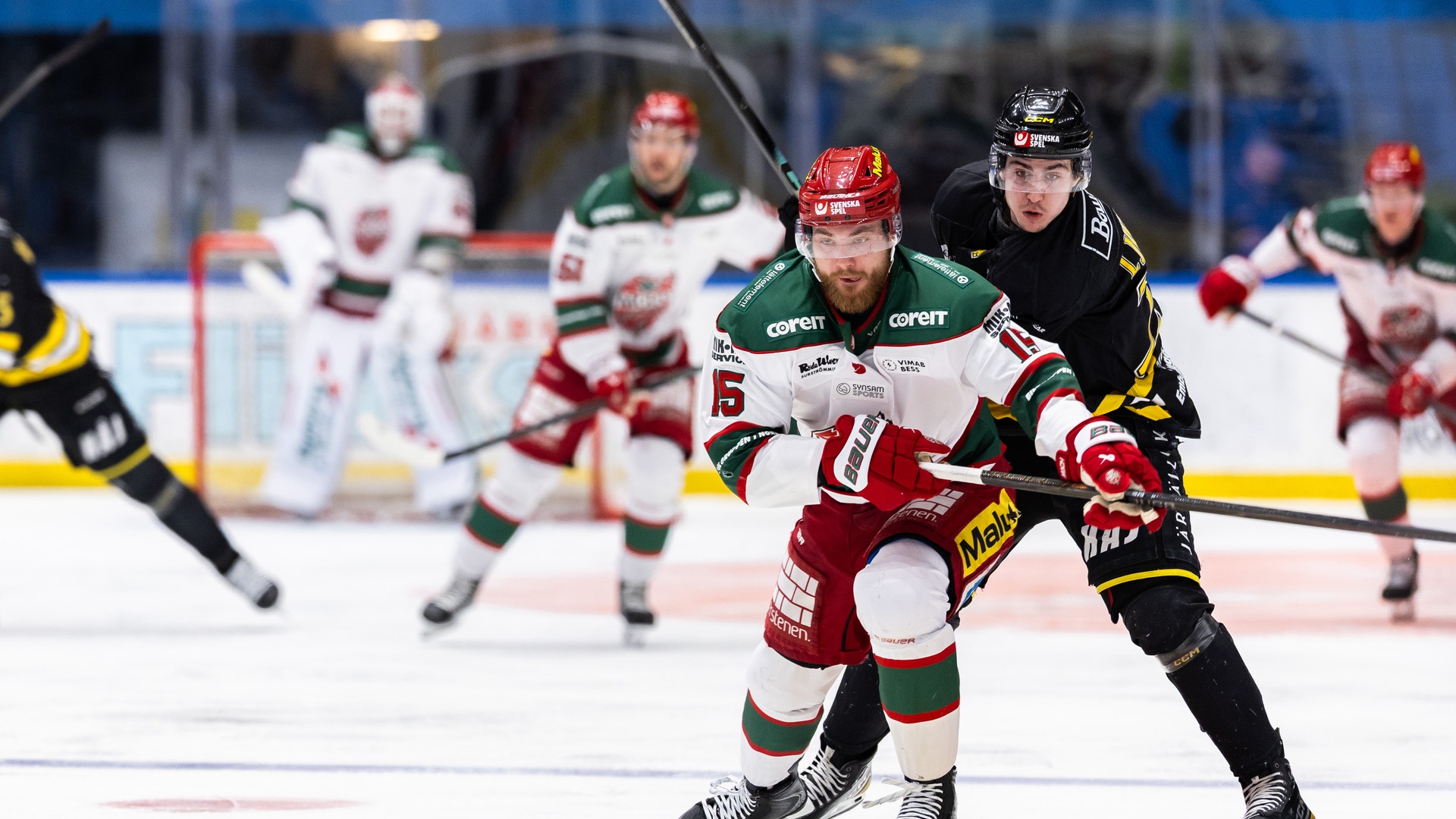Ishockeyspelare från två lag kämpar om pucken under en match.