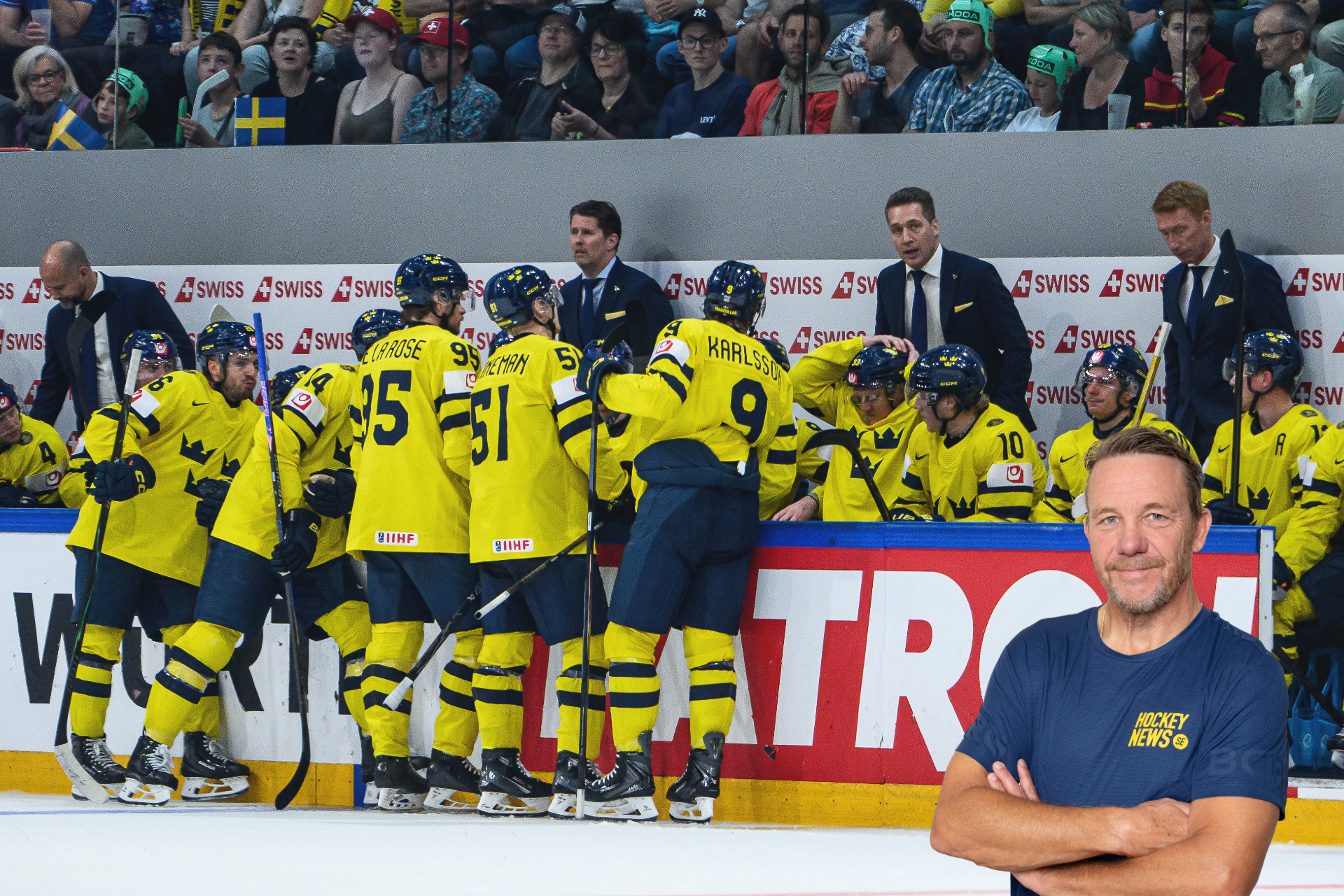 Ishockeylag i gula och svarta trikåer samlat vid bänken under en match. En man i mörkblå t-shirt står i förgrunden med armarna i kors. I bakgrunden syns publik och reklamskyltar.