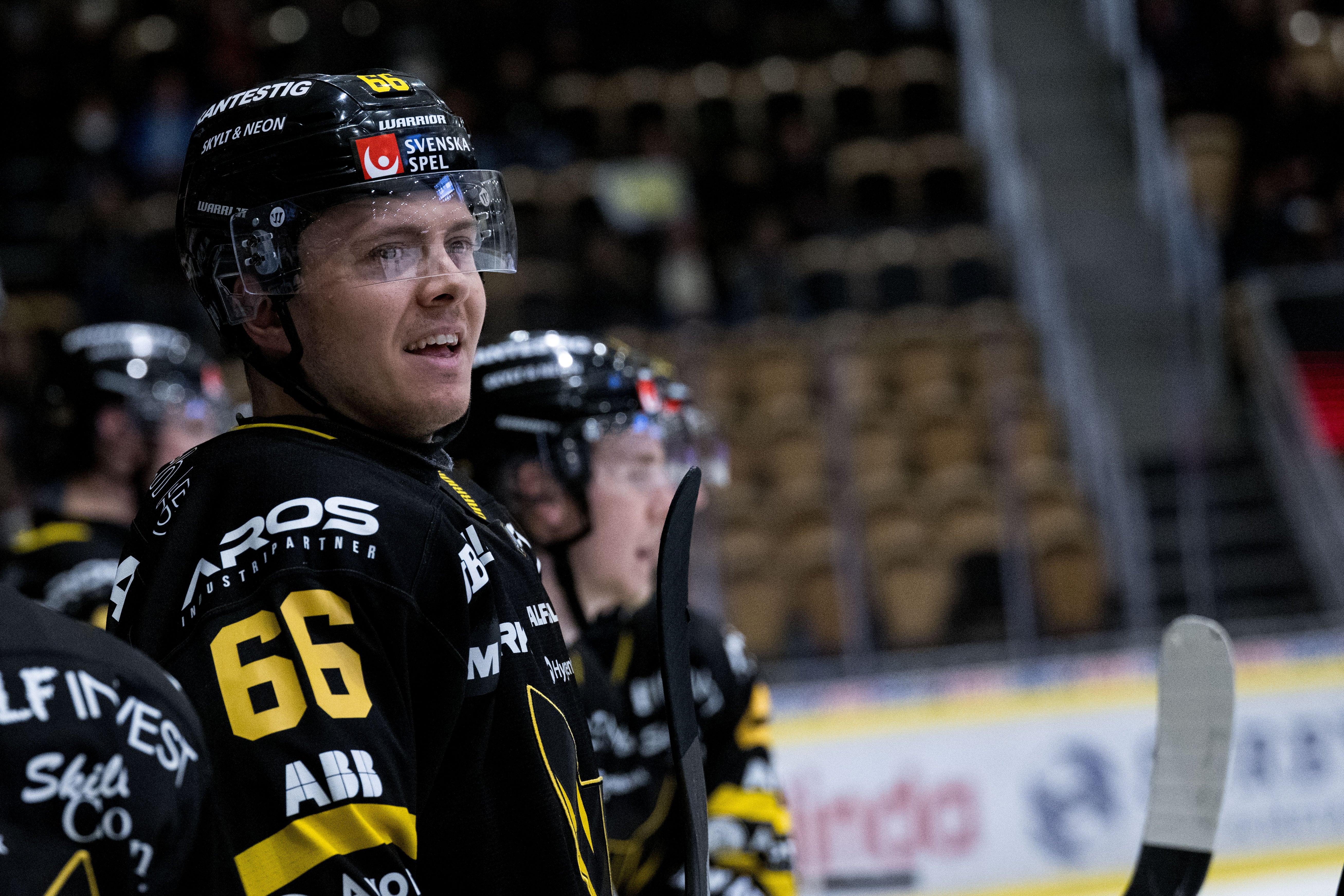 En ishockeyspelare i svart och gul matchdräkt med nummer 66 under en ishockeymatch.