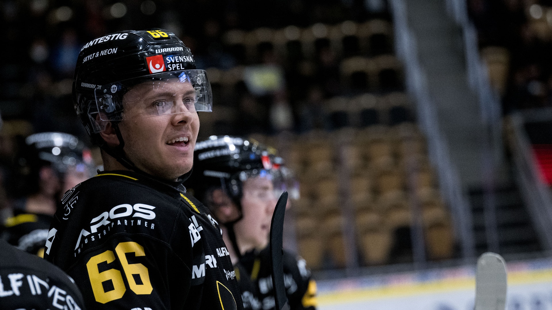 En ishockeyspelare i svart och gul matchdräkt med nummer 66 under en ishockeymatch.