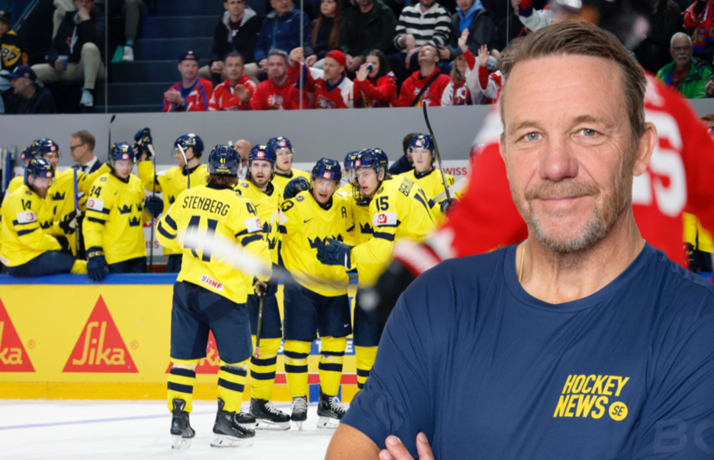 En man i mörkblå t-shirt med Hockey News-logga står framför ett ishockeylag i gul och blå utrustning som sitter på bänken.